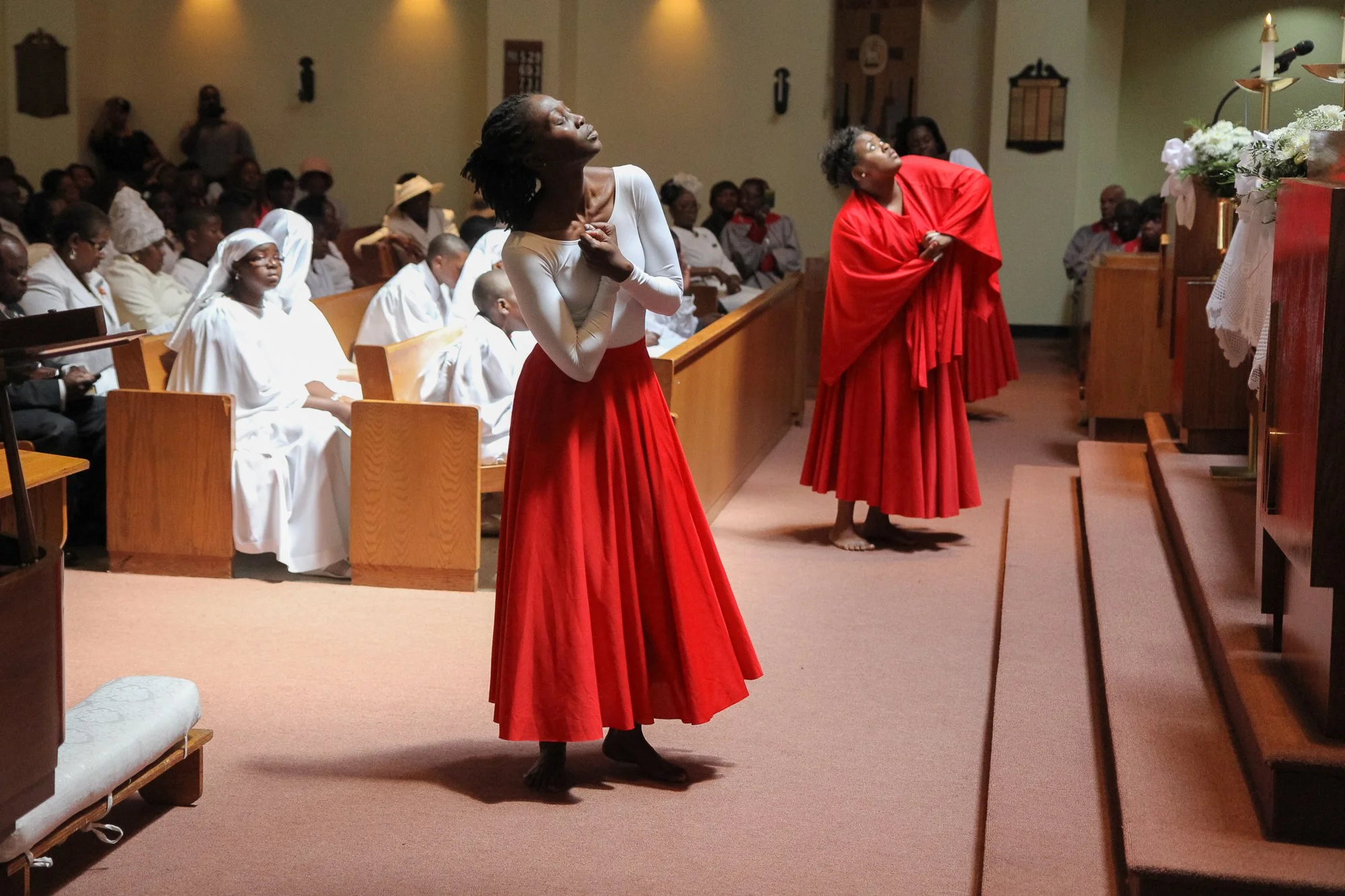 Dancing Dianne performing with dancers in red skirts during a Confirmation event in Harlem in 2011