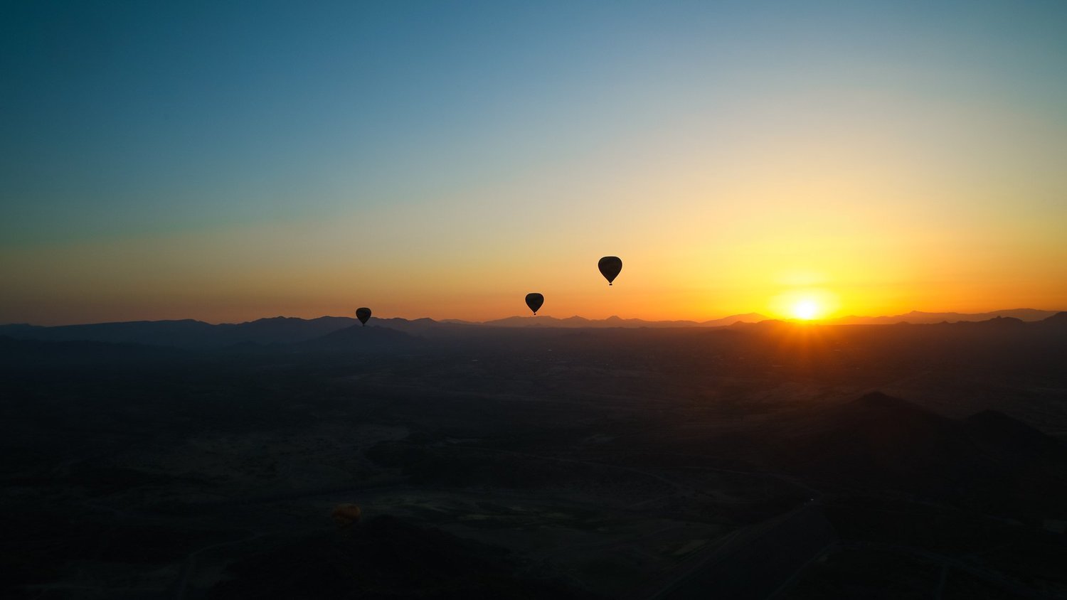Hot-air balloons cross the Sonoran Desert at dawn