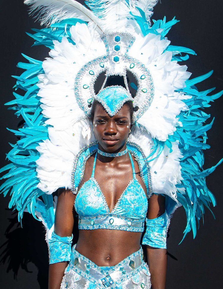 Woman wearing a vibrant blue and white carnival costume with a large feathered headdress.