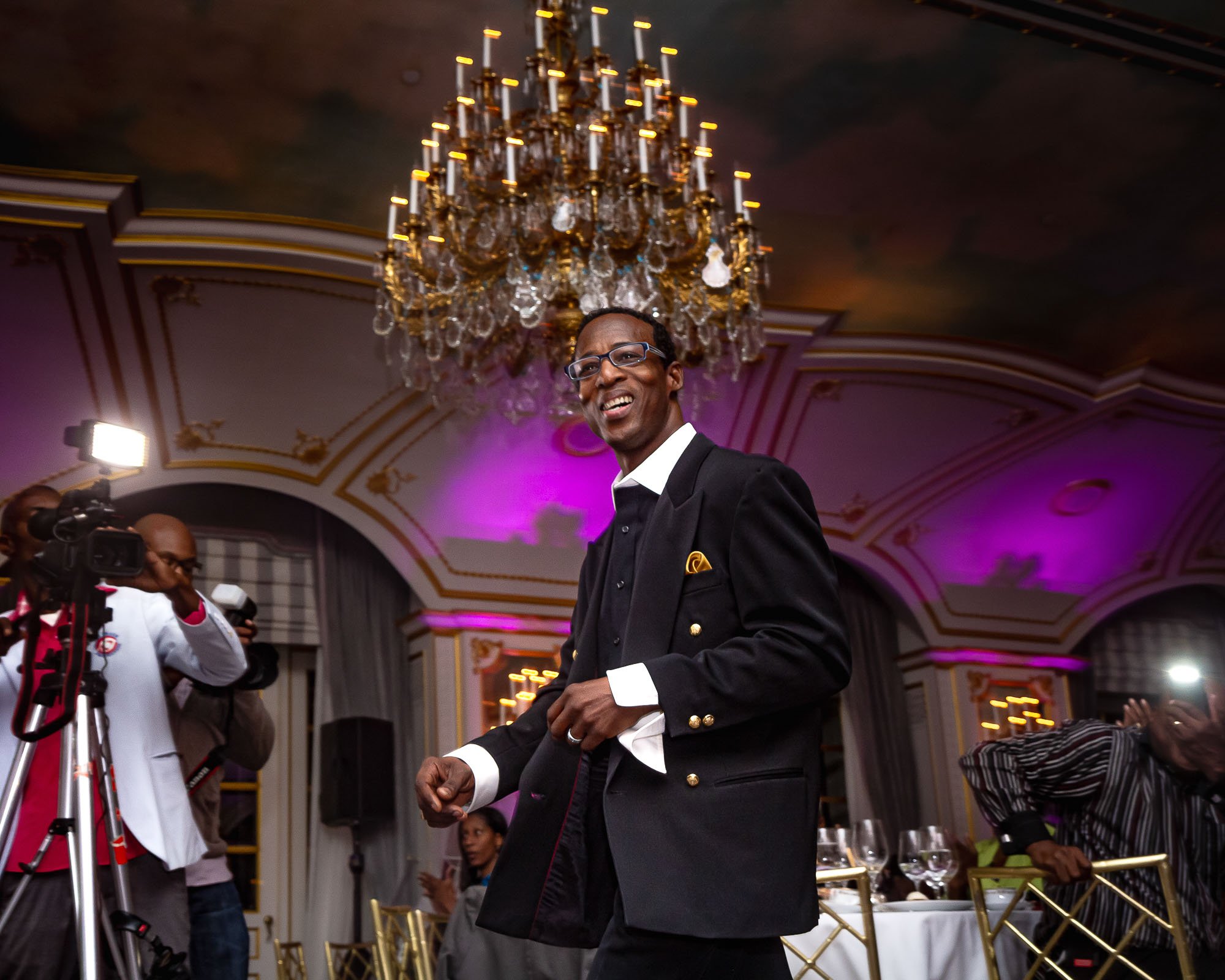 During the African Investment and Development Awards gala, fashion designer Matthew Cashe from Trinidad and Tobago exudes sophistication and charm as he walks through a lavishly decorated dining room at the prestigious St. Regis Hotel in New York. Dr
