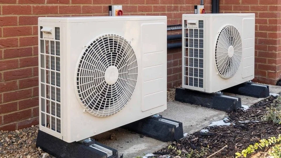 Two outdoor air conditioning units installed outside a brick building