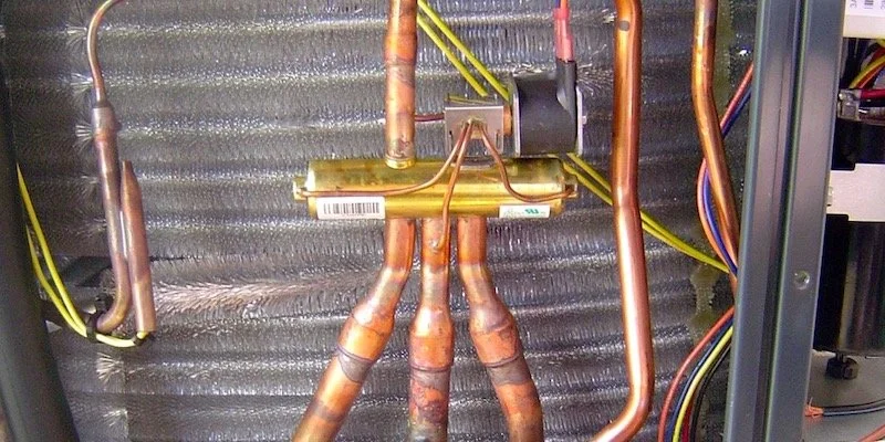 Close-up view of heat pump internal components, showcasing copper tubing, electrical wiring, and a small valve.