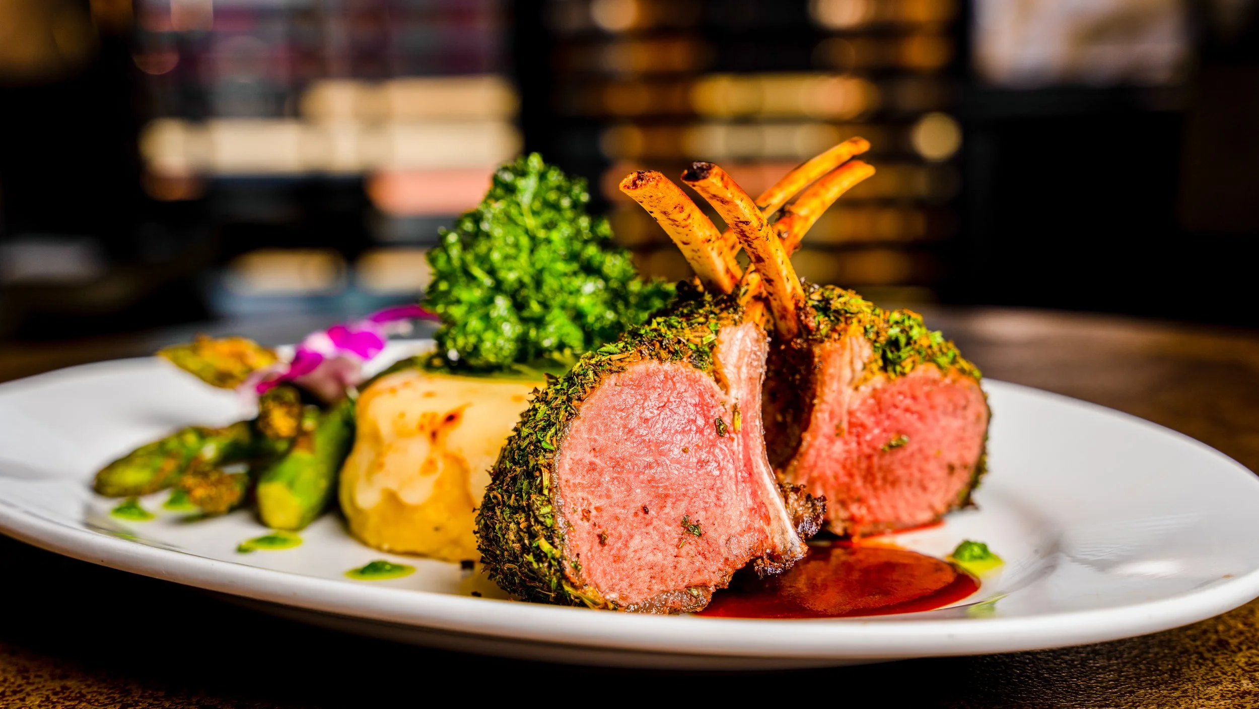Best menu photography rack of lamb medium rare herb crust mashed potatoes grilled asparagus parsley garnish on white plate in New York City and shot by Lumumba David from David Media Group