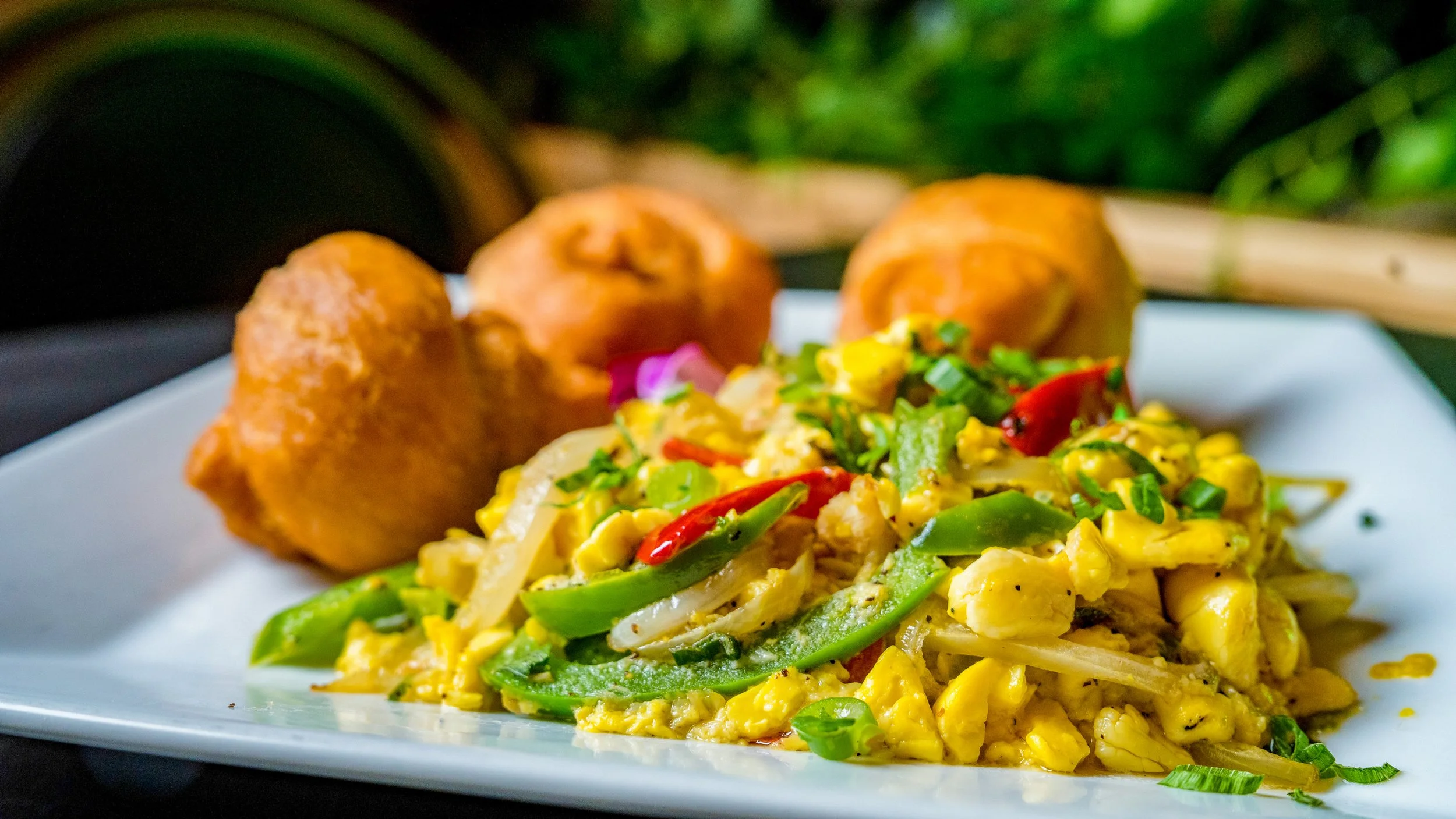 Best breakfast photography scrambled eggs with green bell peppers red chili peppers green onions and side fritters on white plate in New York City and shot by Lumumba David from David Media Group