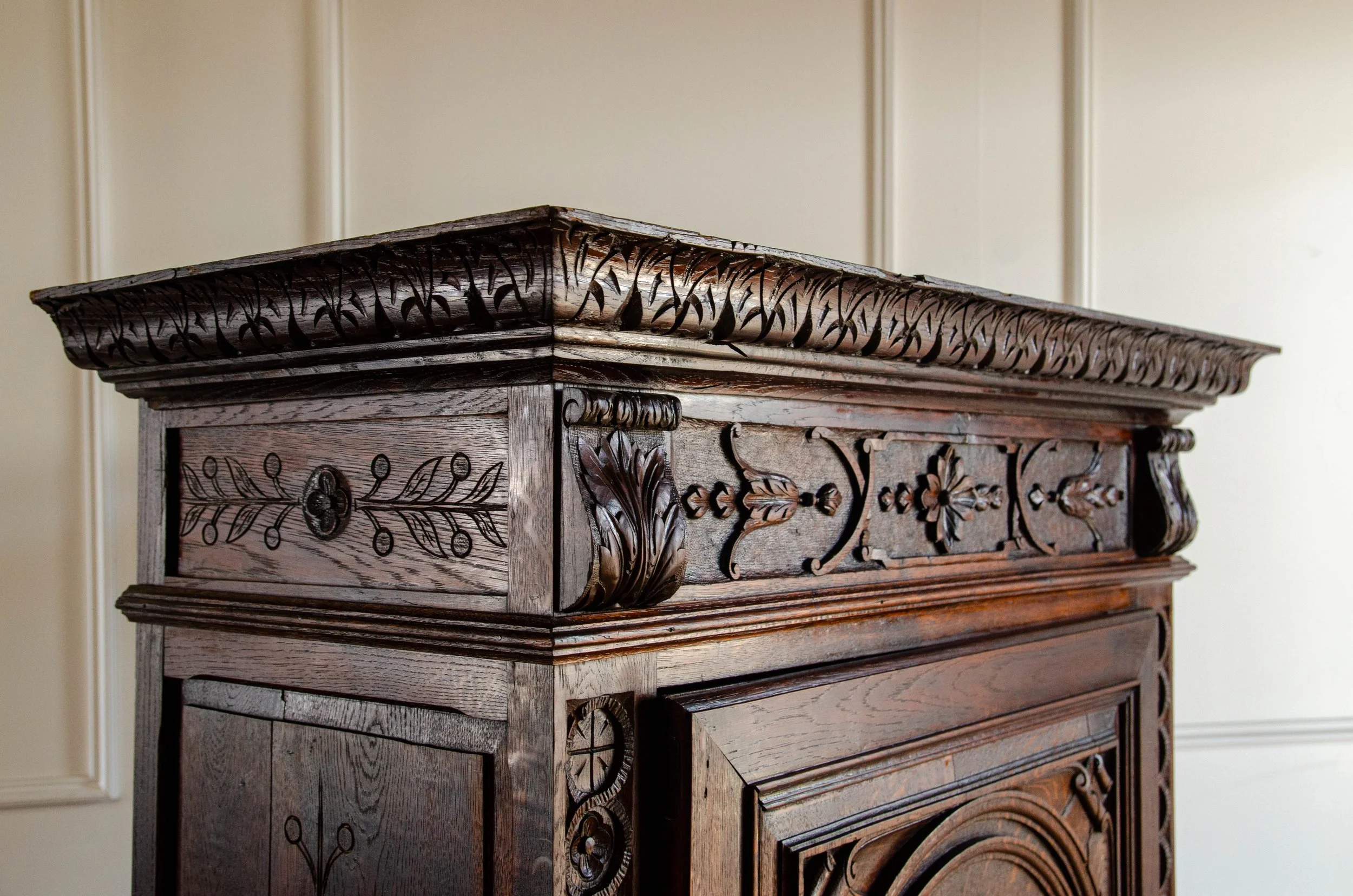 Close-up of an ornate, carved wooden antique cabinet or piece of furniture with decorative floral and leaf patterns.