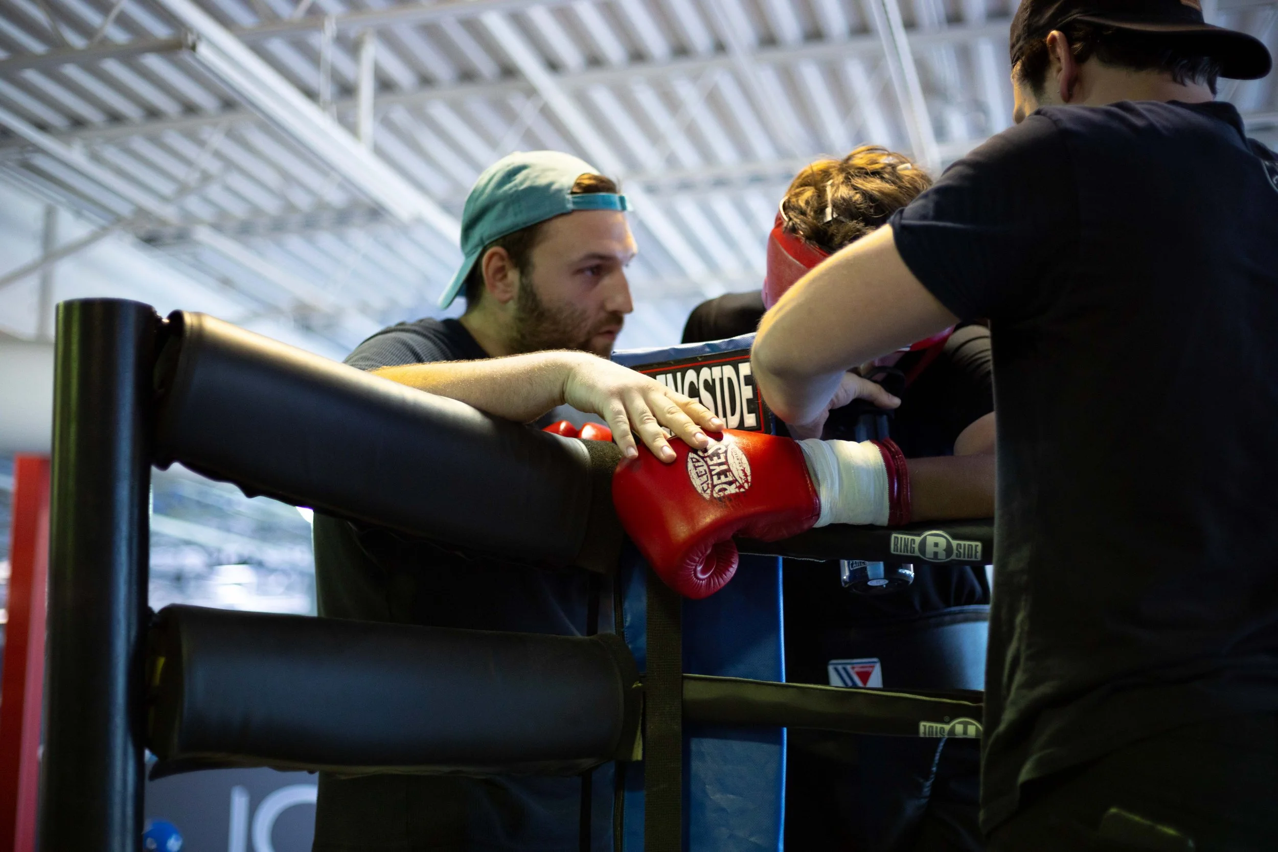 A boxing coach and trainer giving instructions to a boxer who is training in a boxing ring.