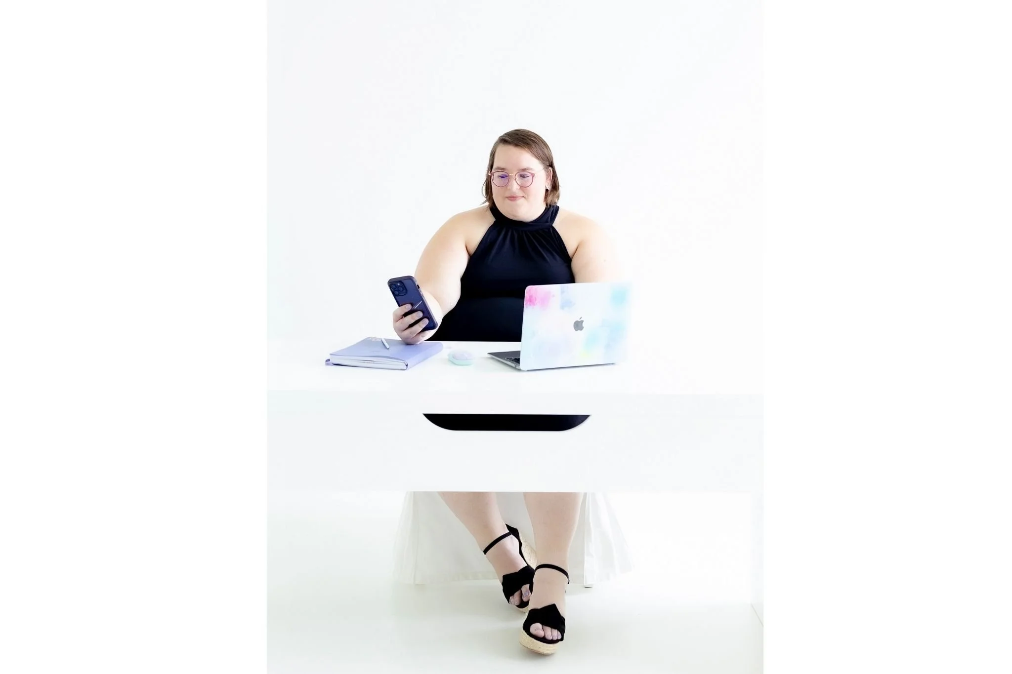 Image of Sammy Bohannon of Bohannon Virtual Solutions sitting at a desk and scrolling through her phone.