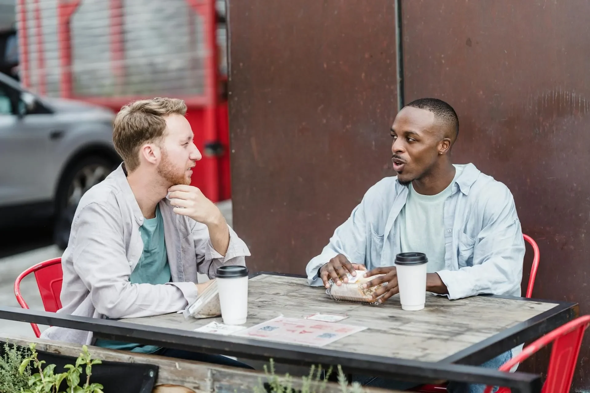 two men gay couple going to counselling chatting over lunch outside.