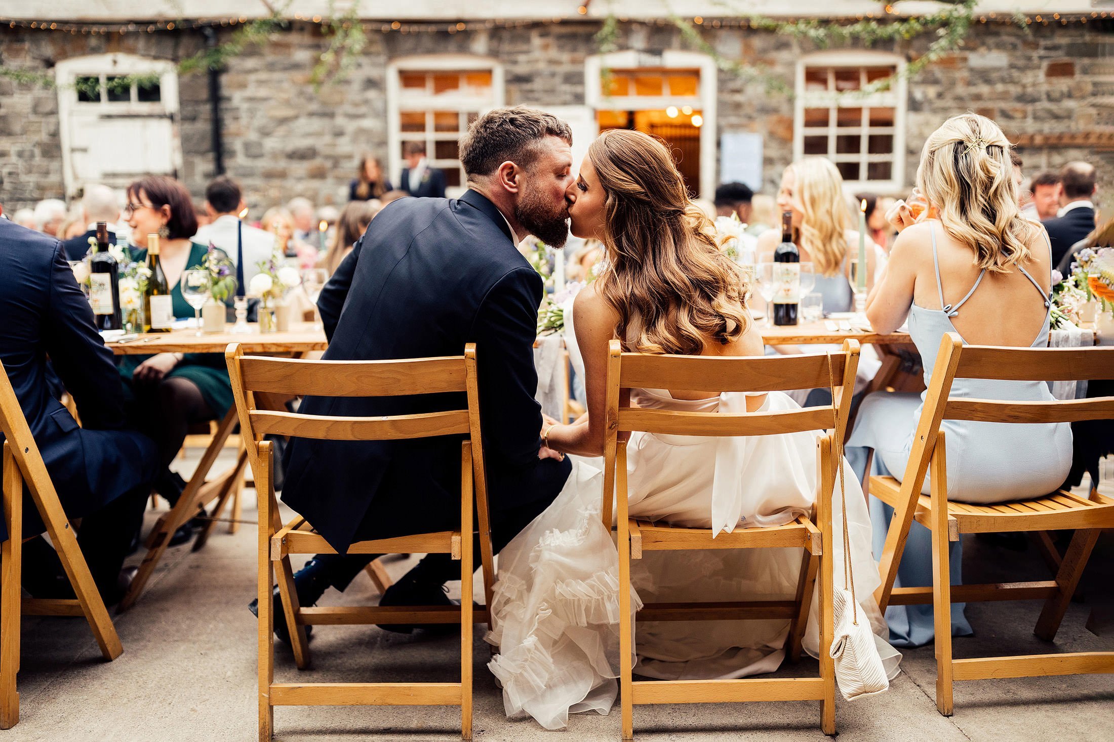 couple kiss at table plas Dinam wedding