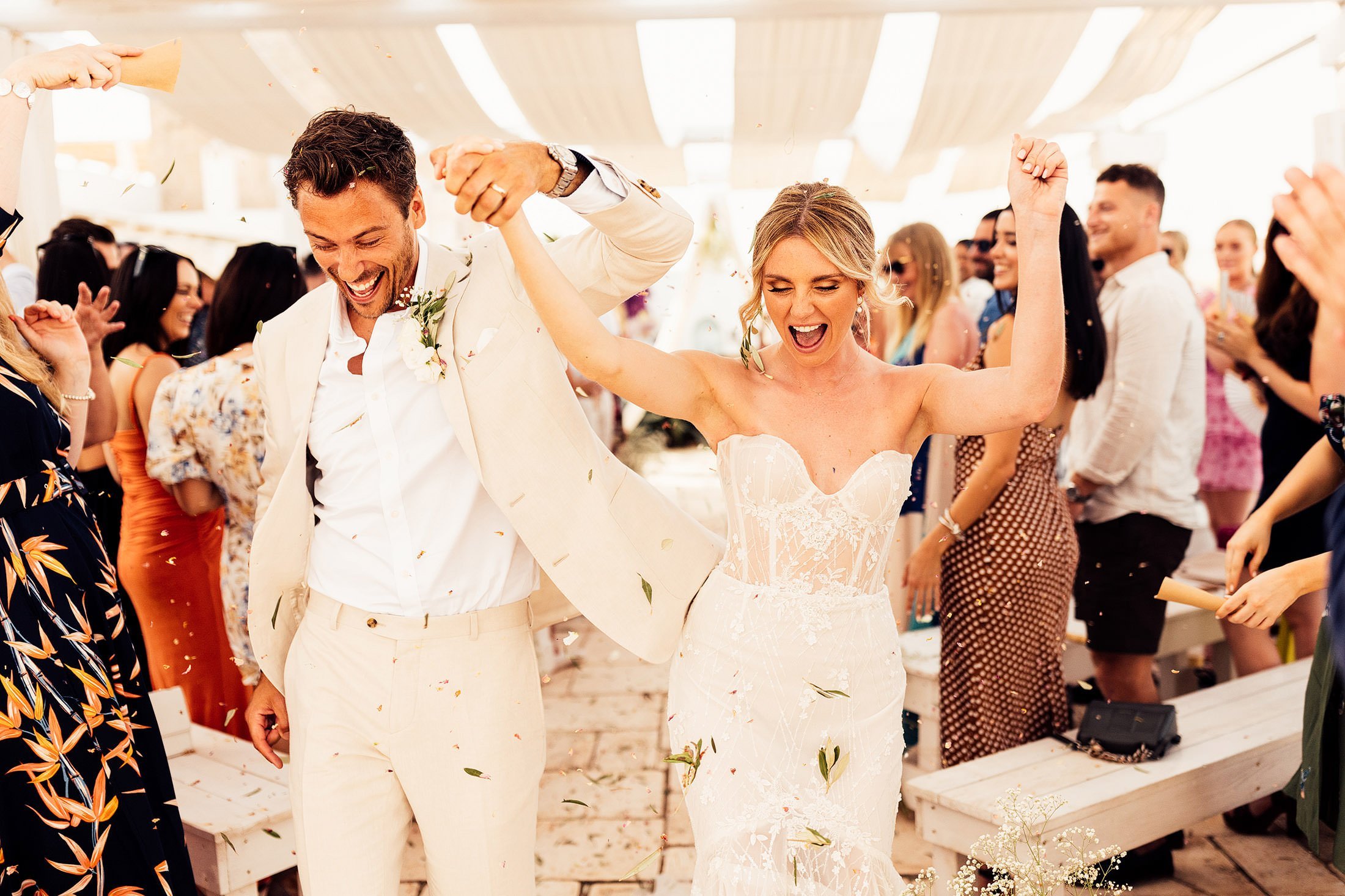 couple dance down isle whilst guest throw olive leave confetti