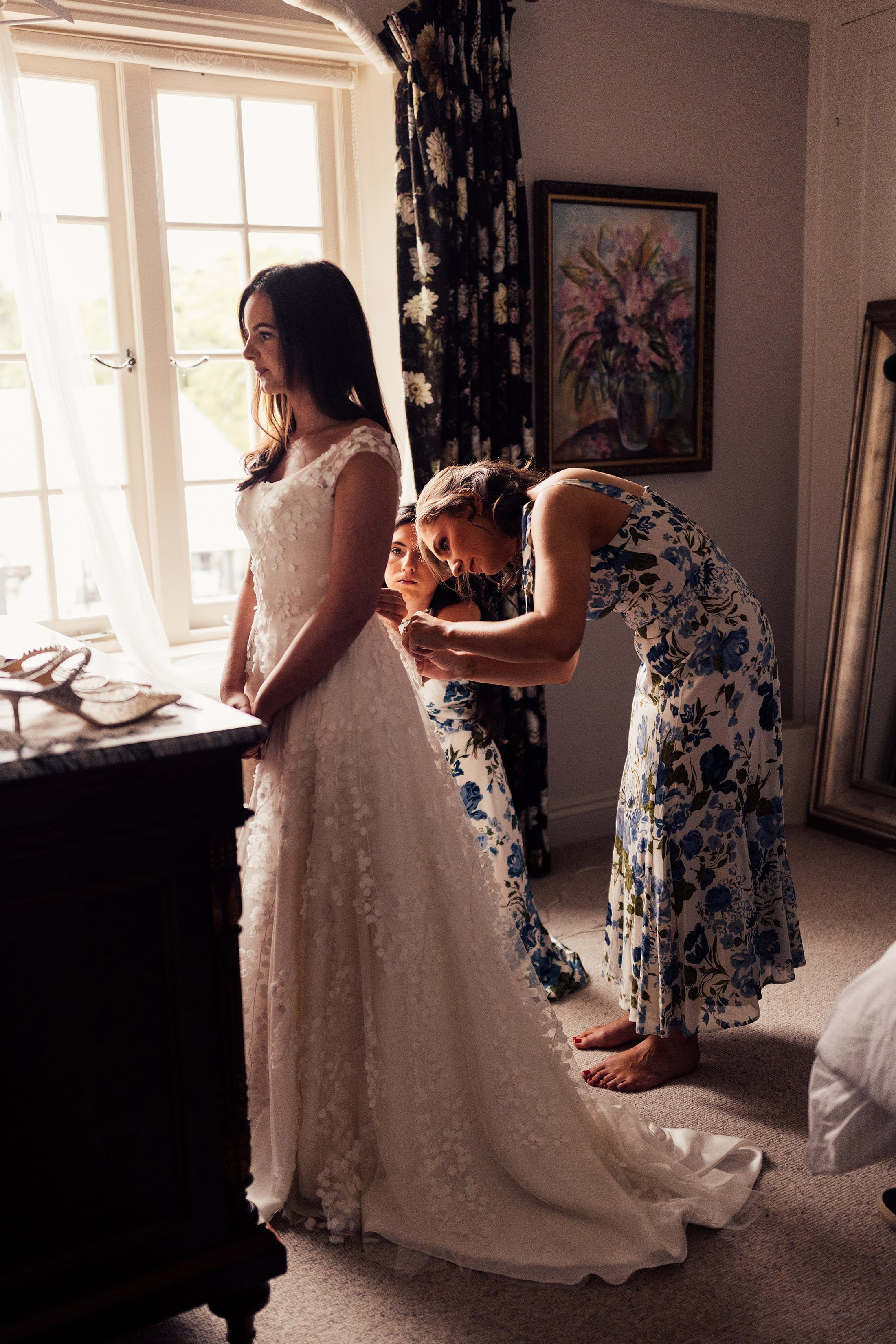 bridesmaid helps bride into phillipa lepley dress