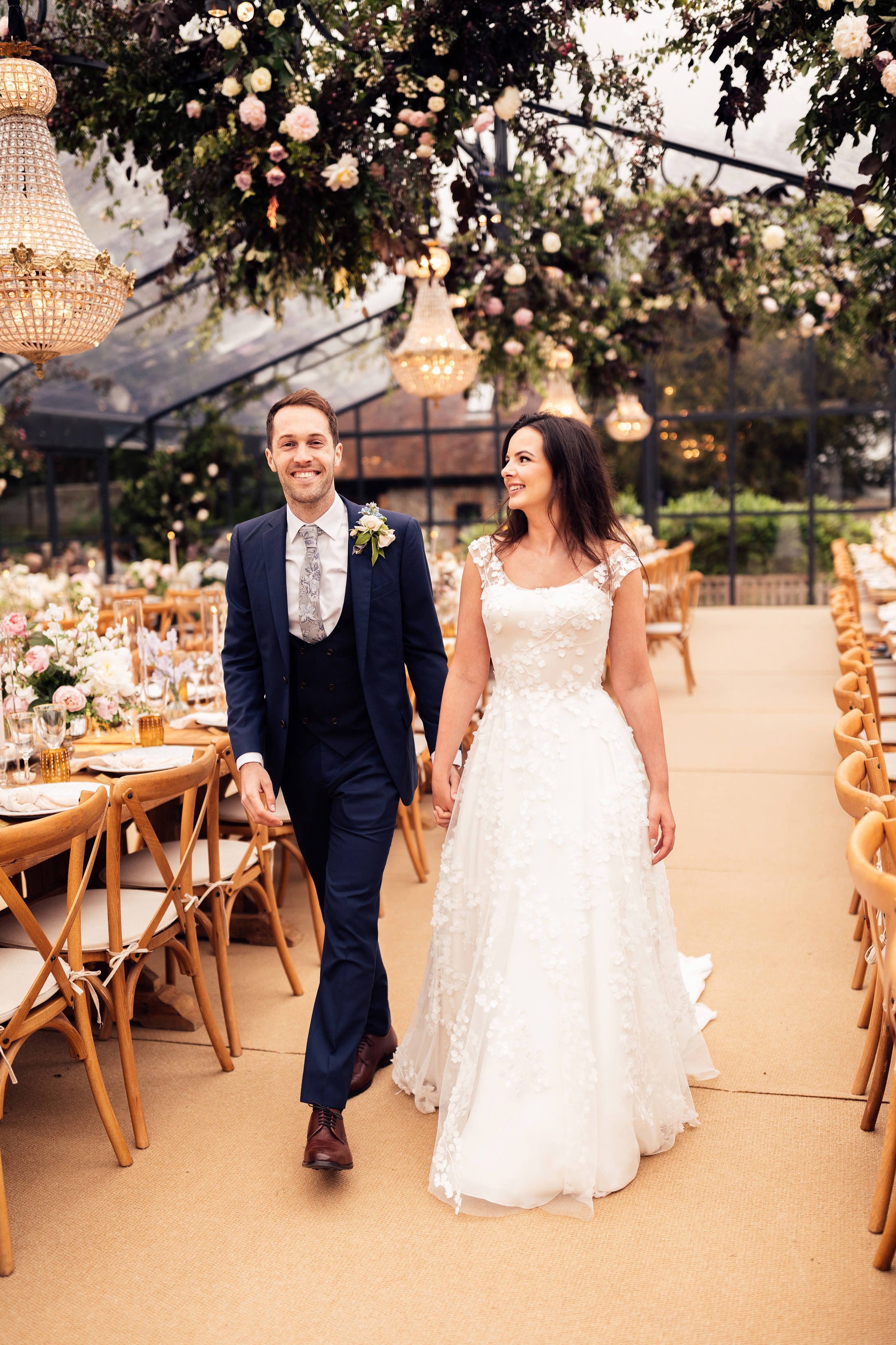 bride and groom walk through orangery glass house wedding