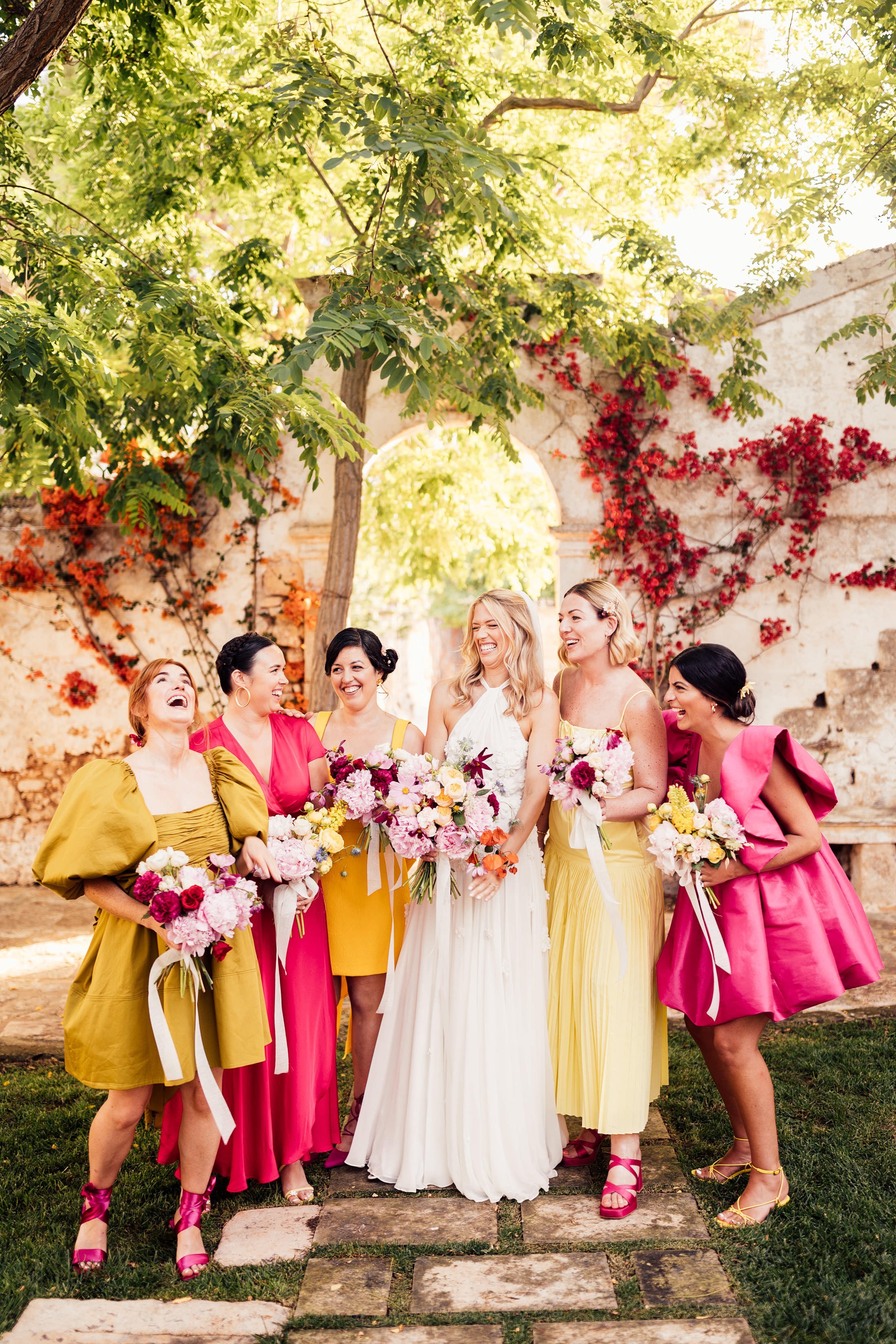 bride smiling with bridesmaids in mix matched colourful dresses