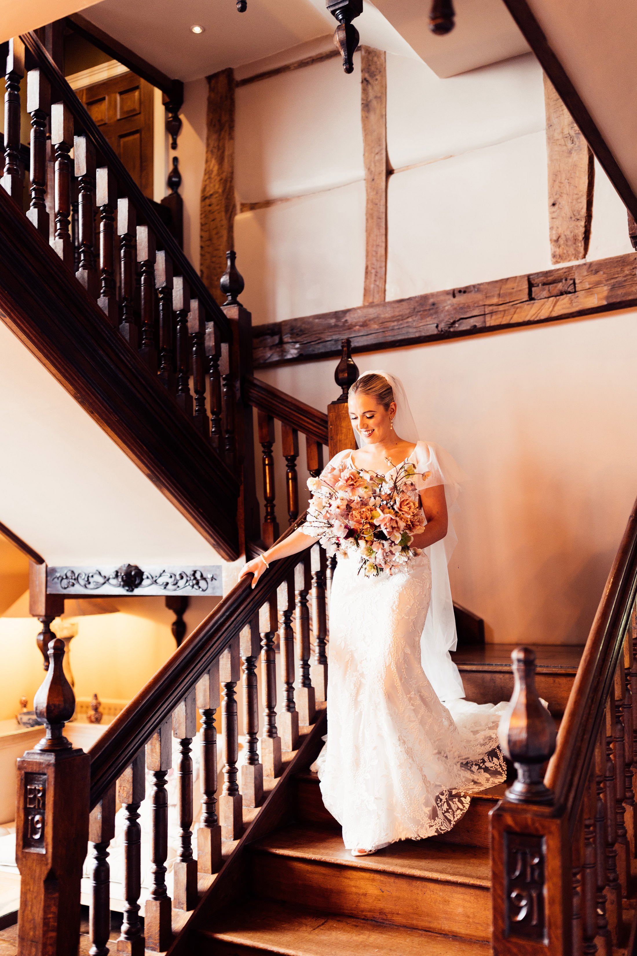 bride walks down staircase with big bouquet 