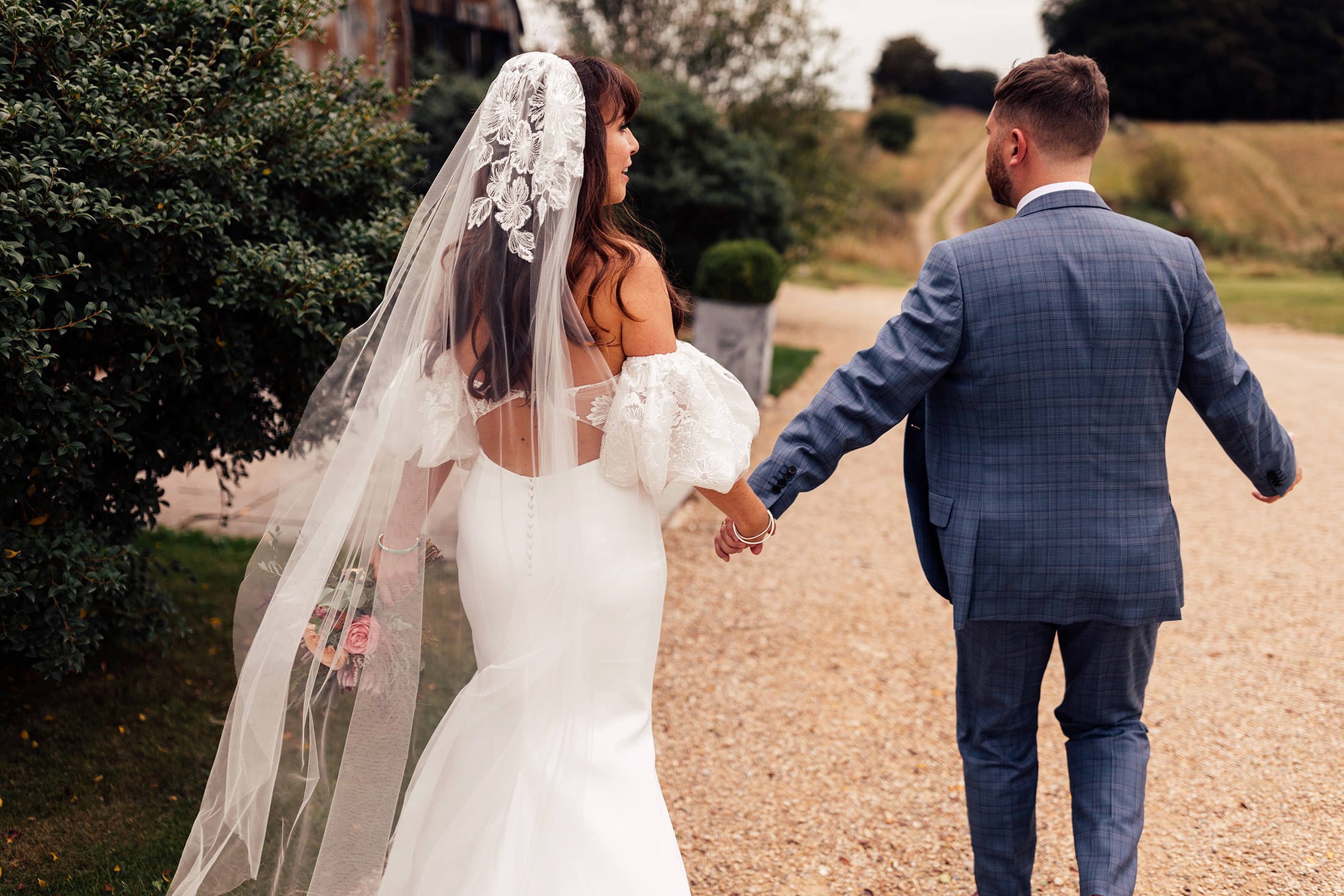 stylish couple walk into cotswold wedding venue