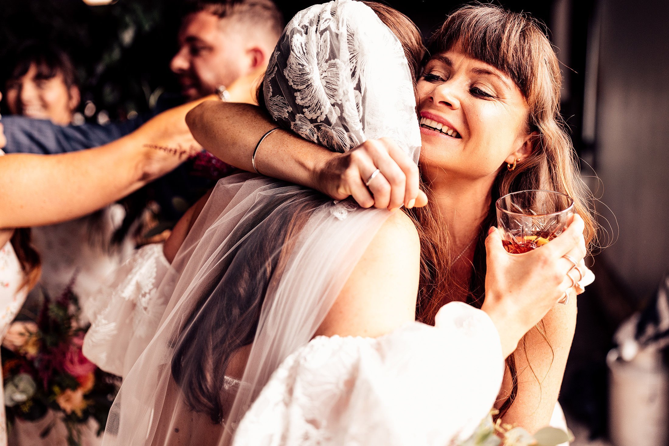 bridesmaid hugs bride in lace embellished veil