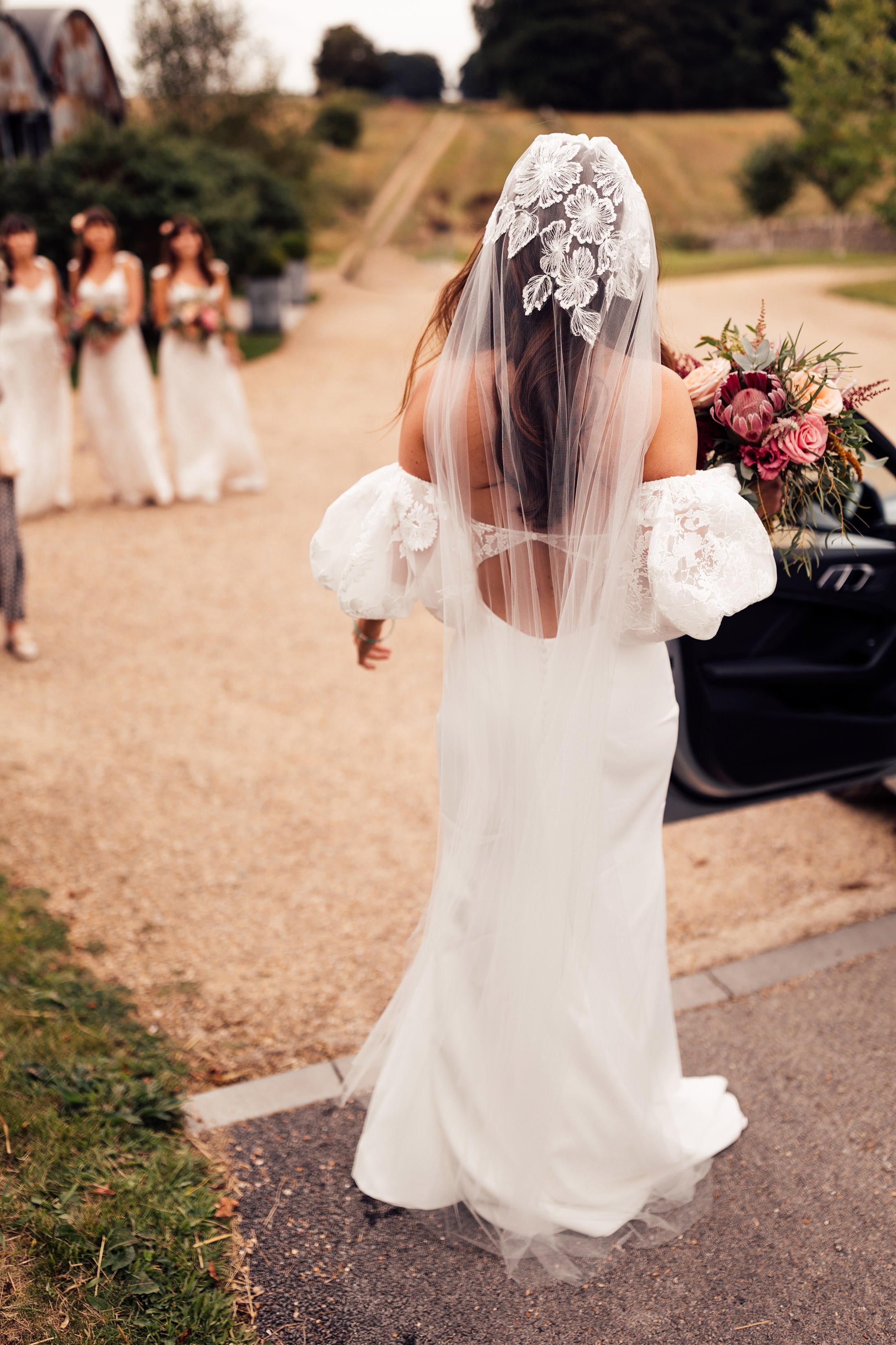 bride holds floral bouquet wearing lace embellished veil 