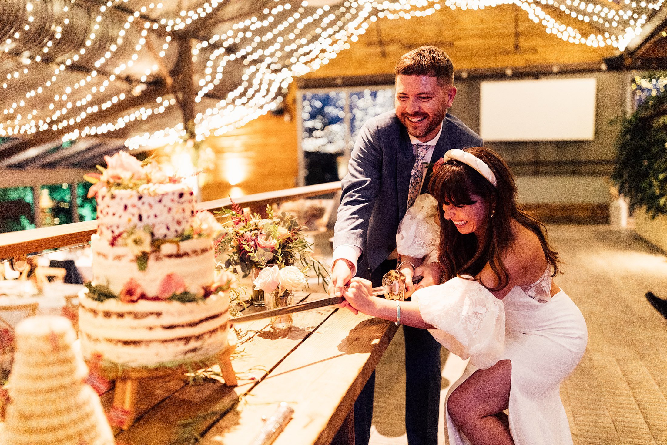 bride and groom cut wedding cake with nordic sword