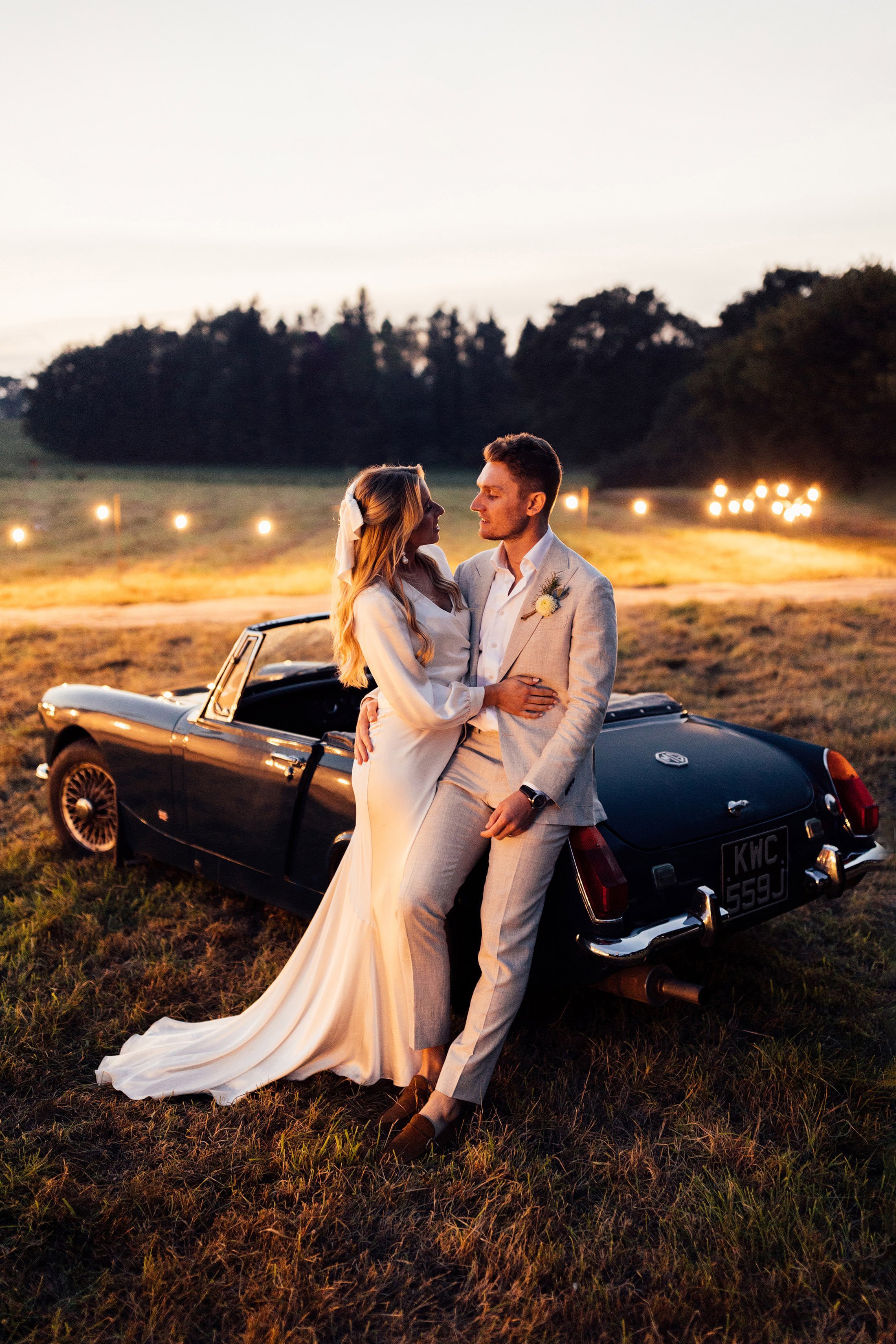 couples portrait at dusk in front of vintage MG car