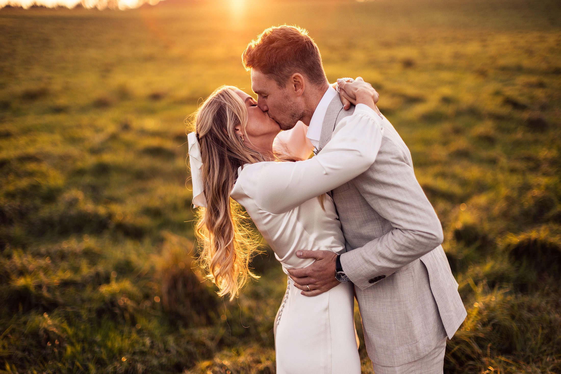 couple kiss at sunset in field