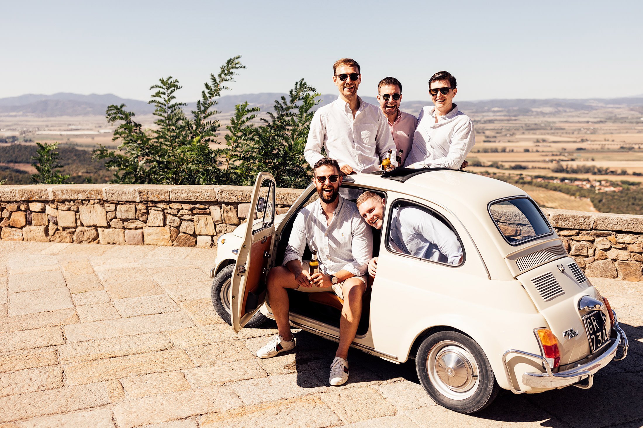 groomsmen pose with vintage fiat in Tuscany