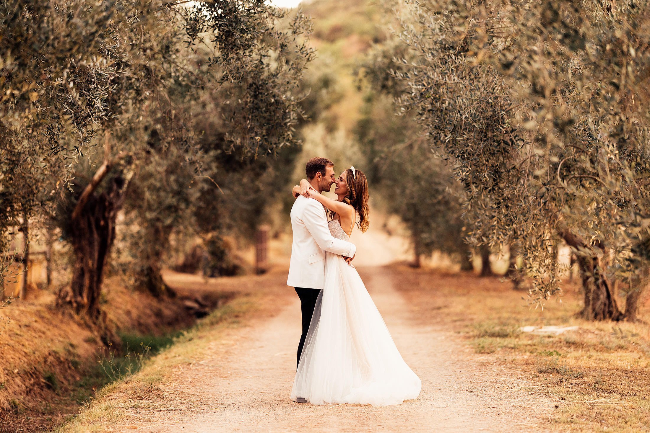 couple embrace in olive grove at la Pescaia resort