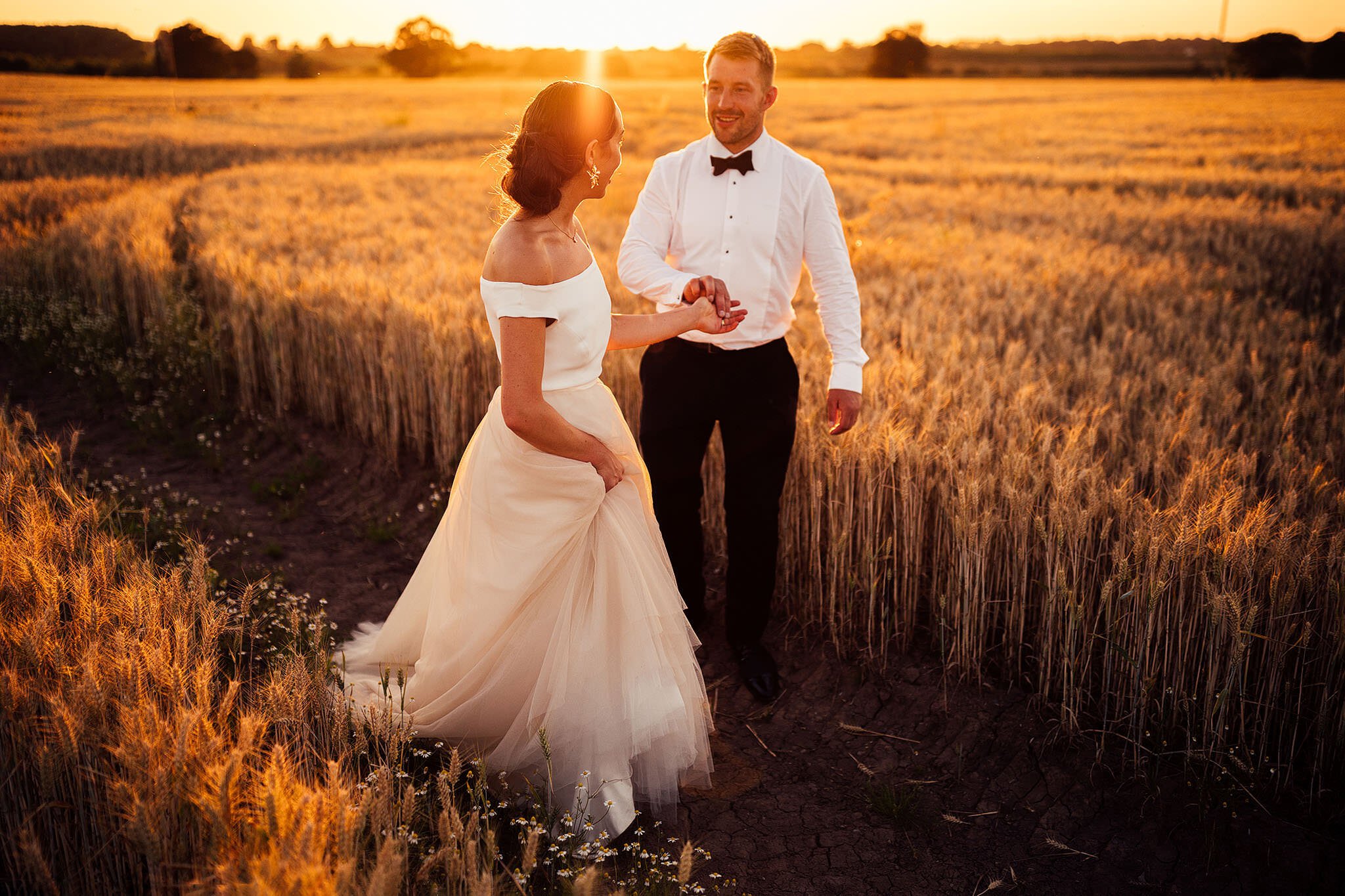 couple walking in field at sunset 