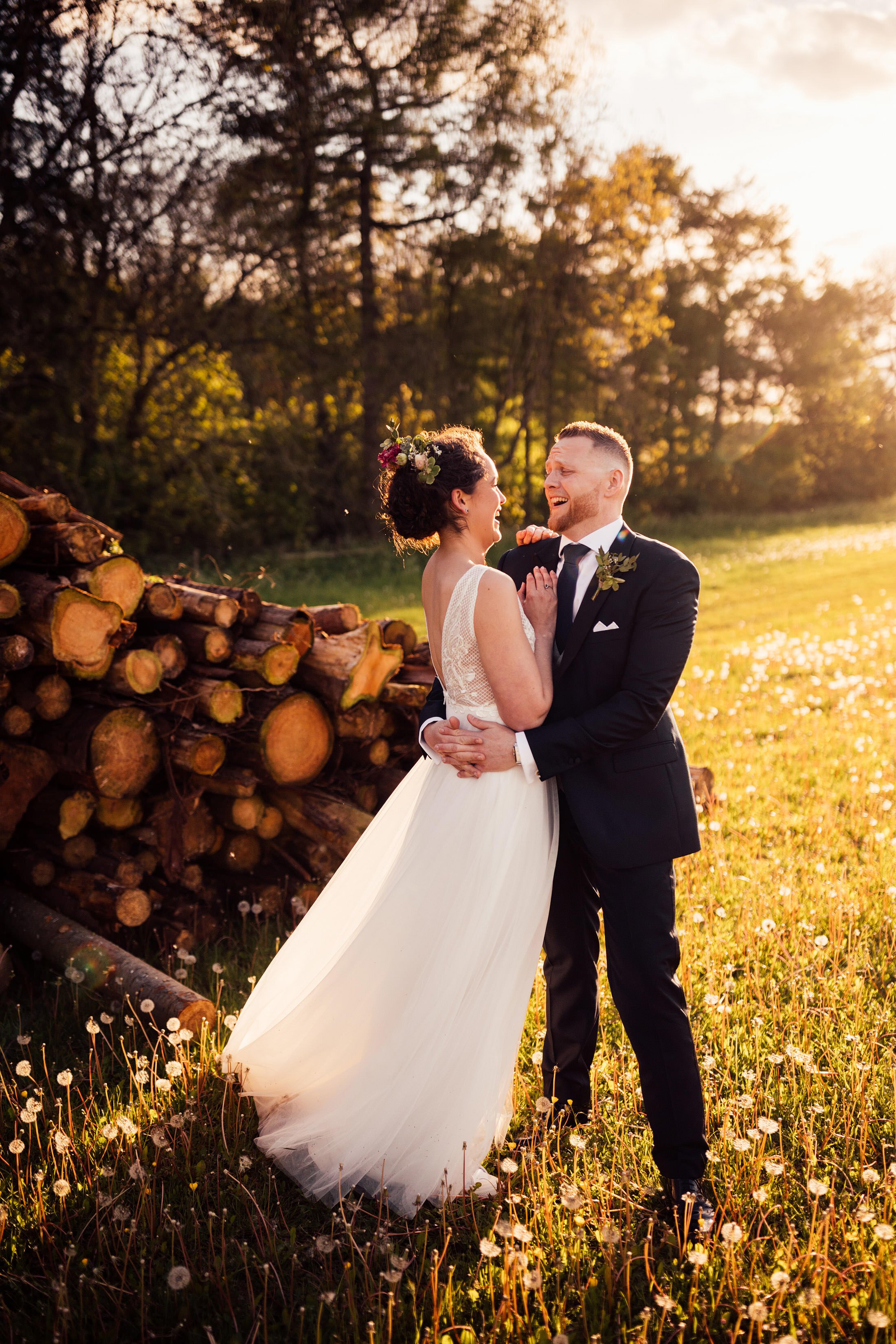 couple embrace in front of log pile