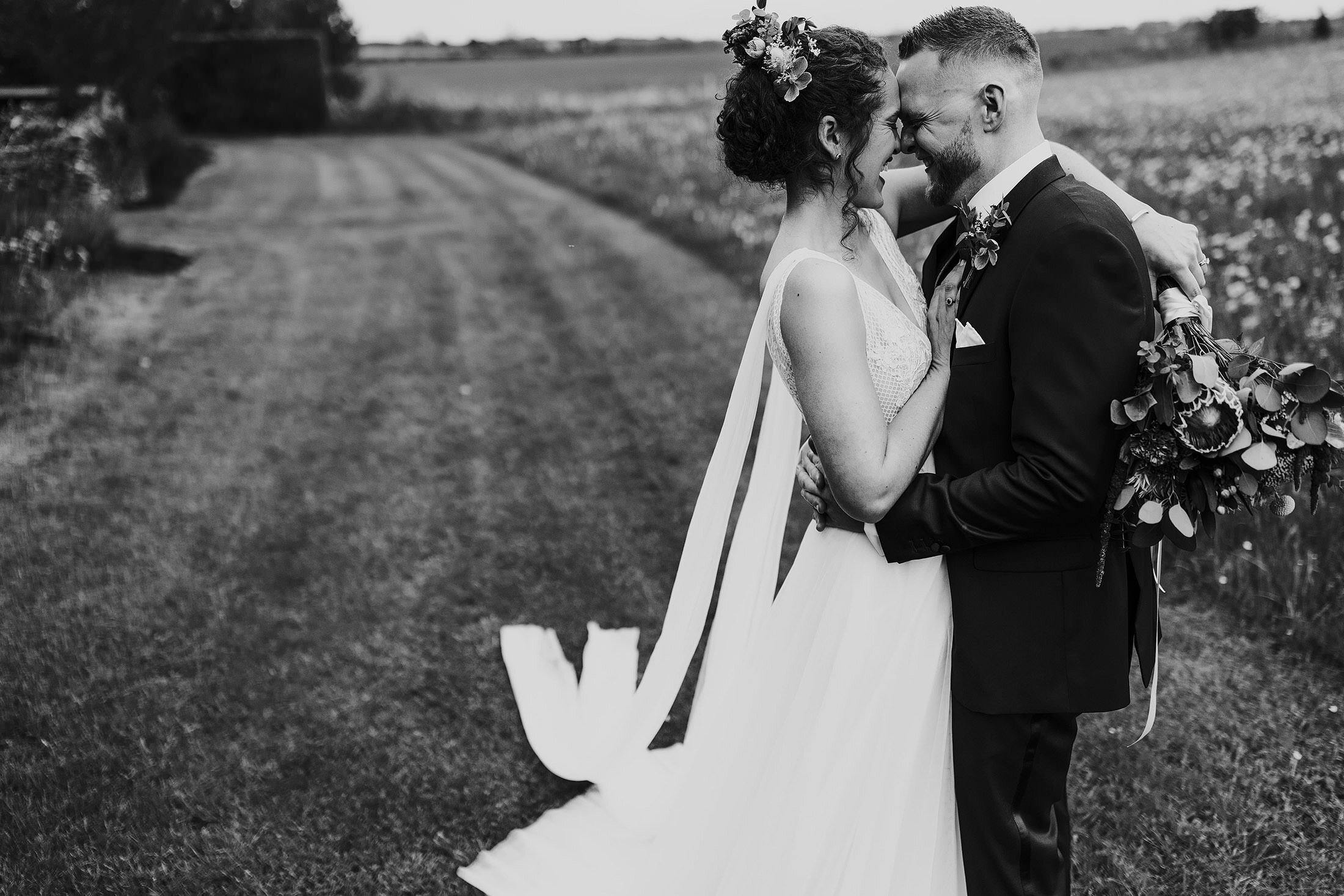 couple embrace in field outside Cripps barn