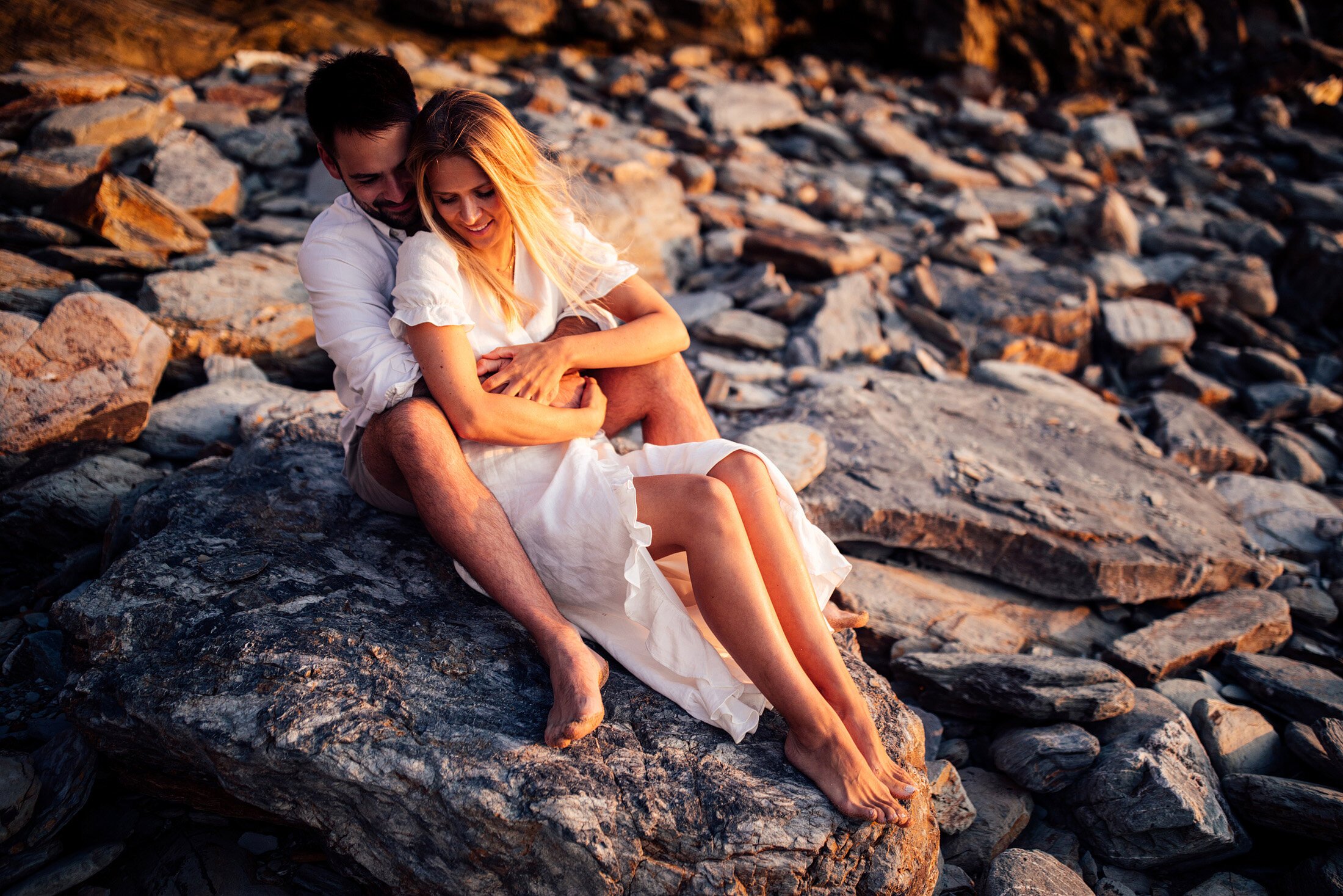 couple sit by rocks at Watergate bay beach