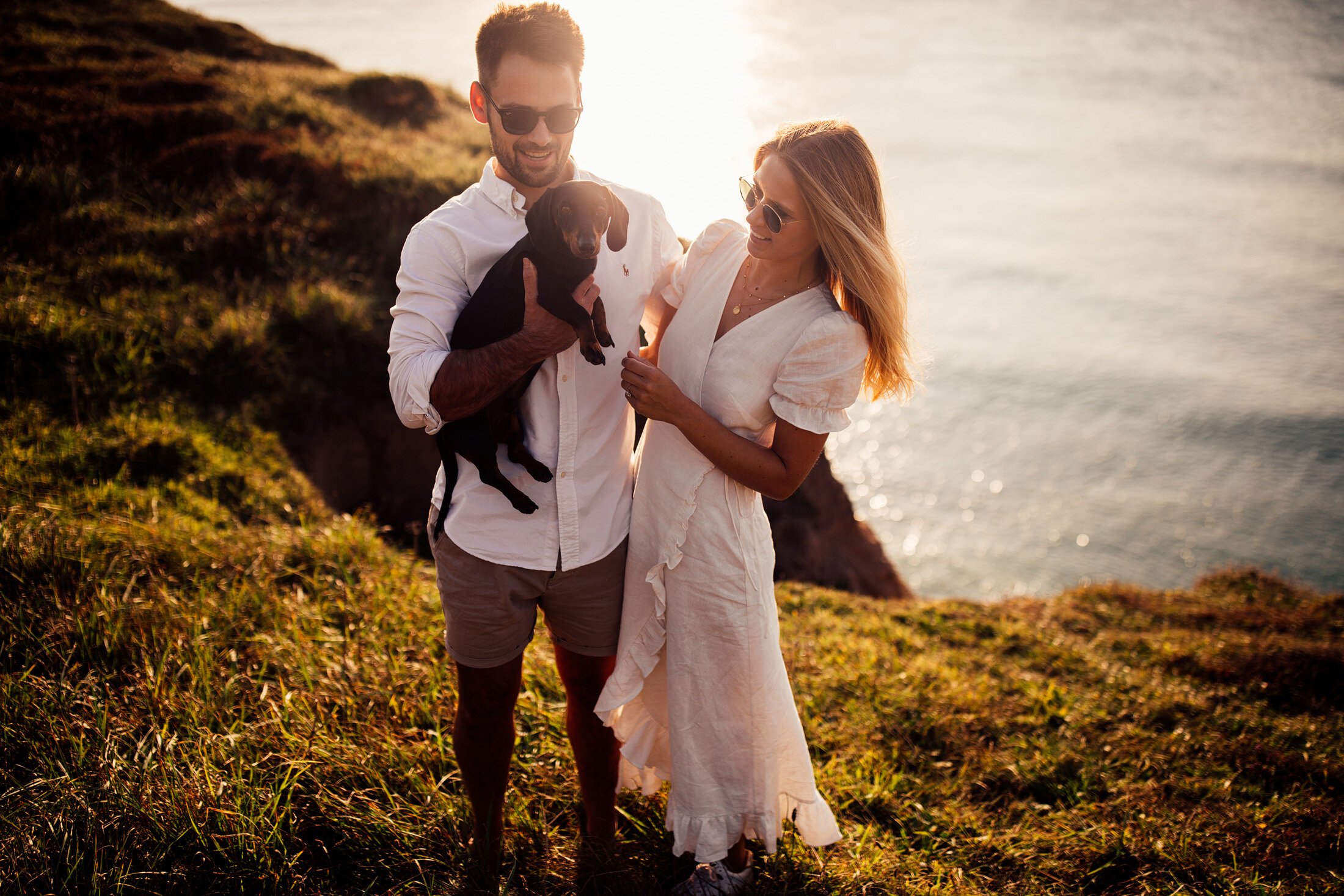 couple hold  dachshund on cornwall engagement shoot