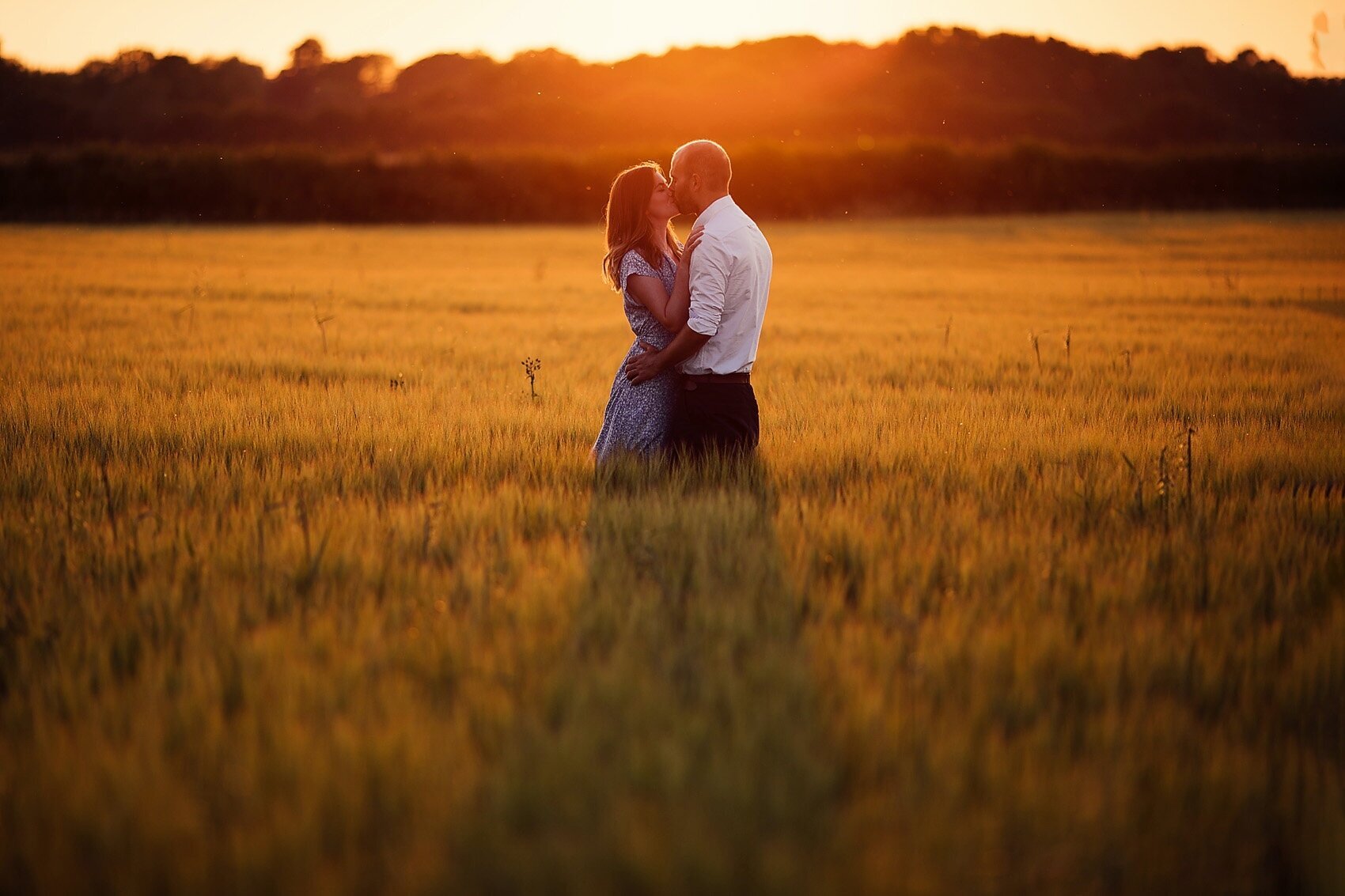 couple embrace in field at sunset in cotswolds