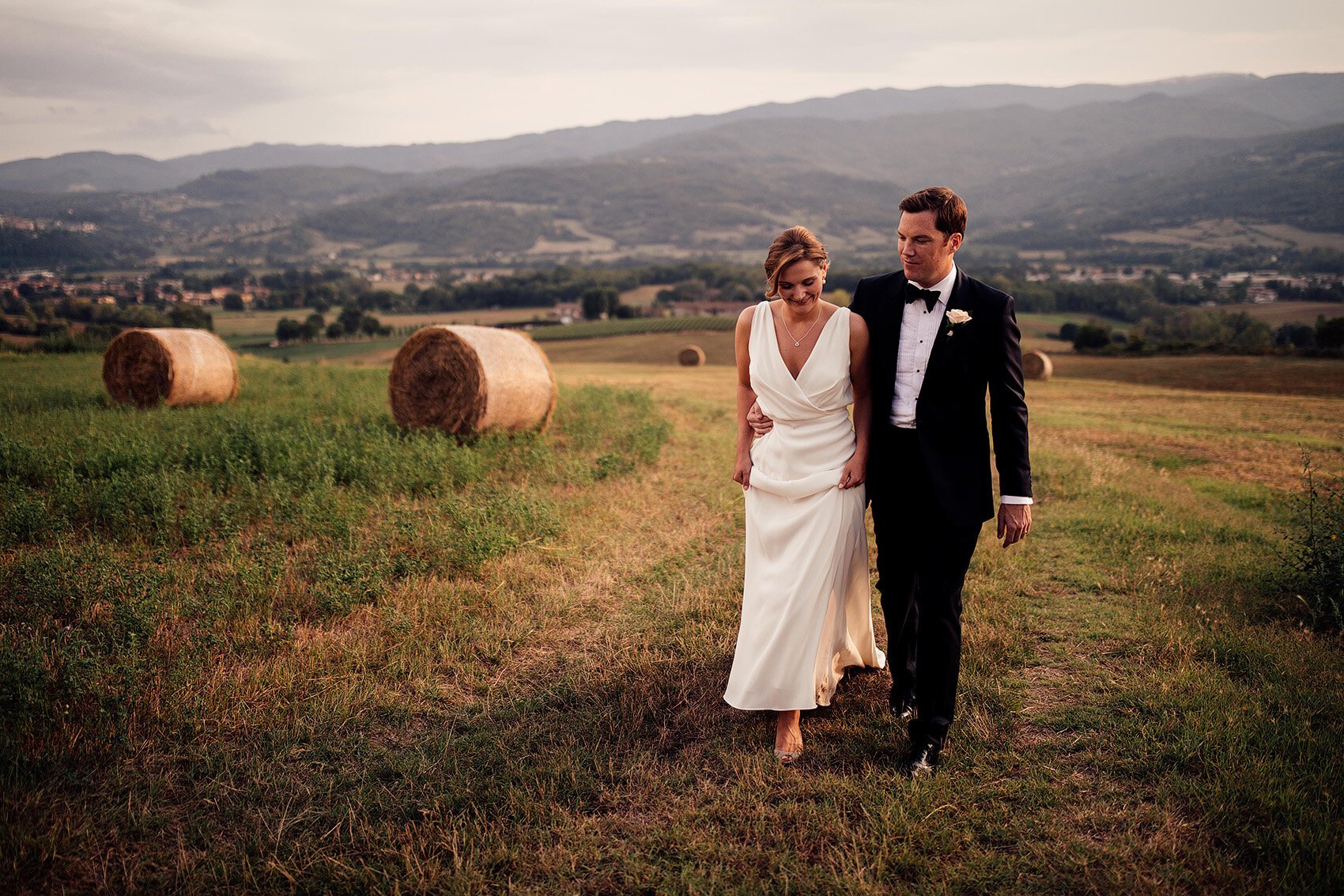 bride and groom walk in italian fields 