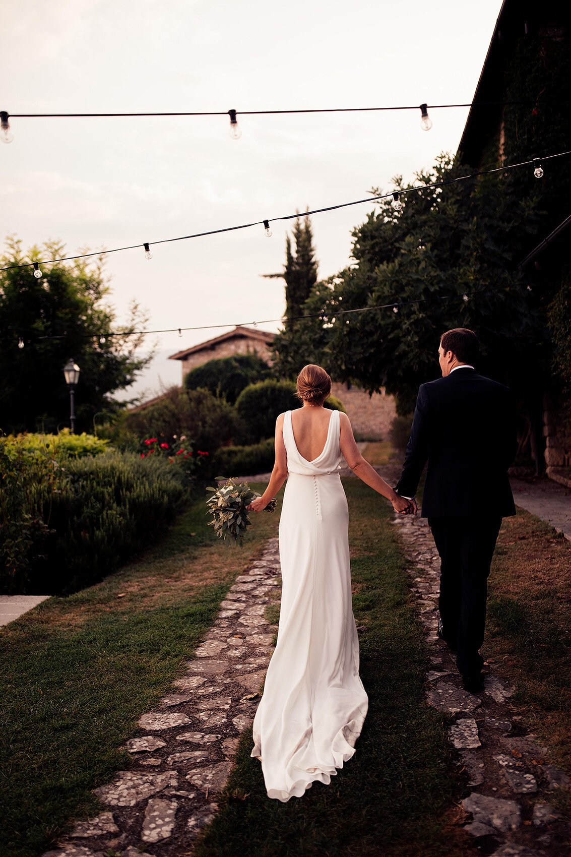 bride in pronovias dress walks with groom in borgo corsignano