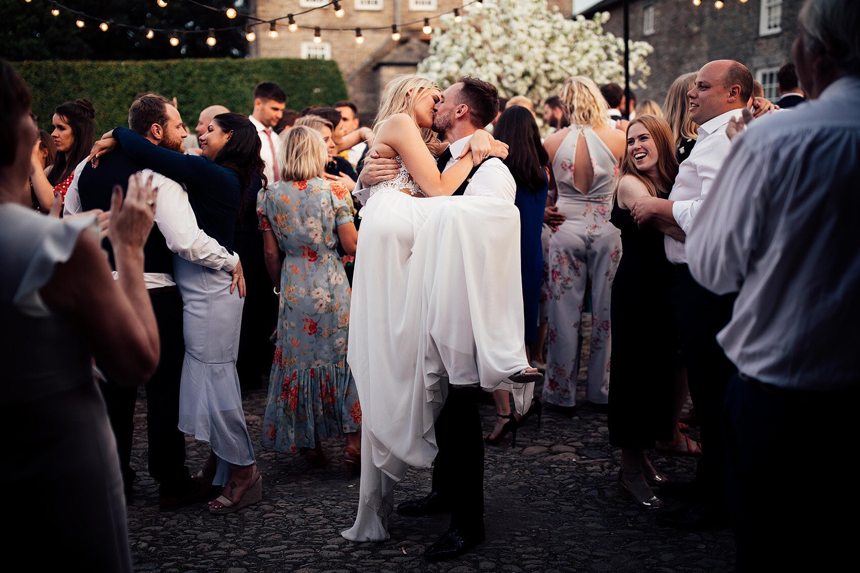 Groom picking up his bride during outdoor wedding first dance