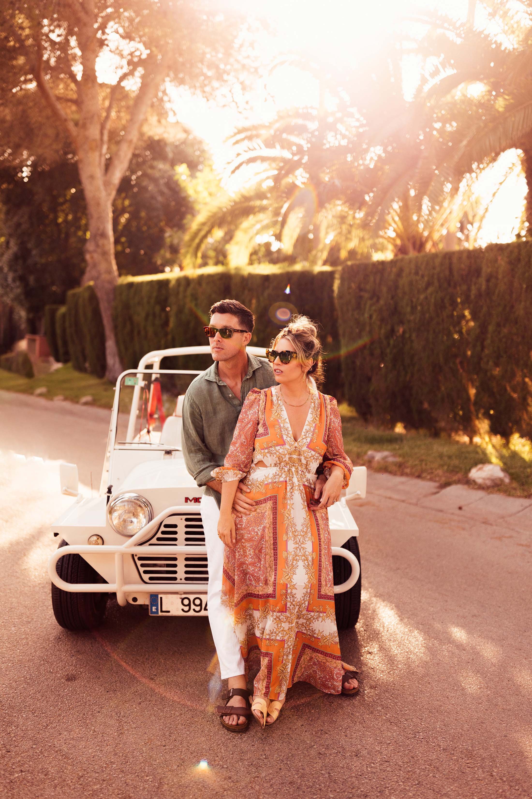 couple pose for photo sitting on white Moke in spain