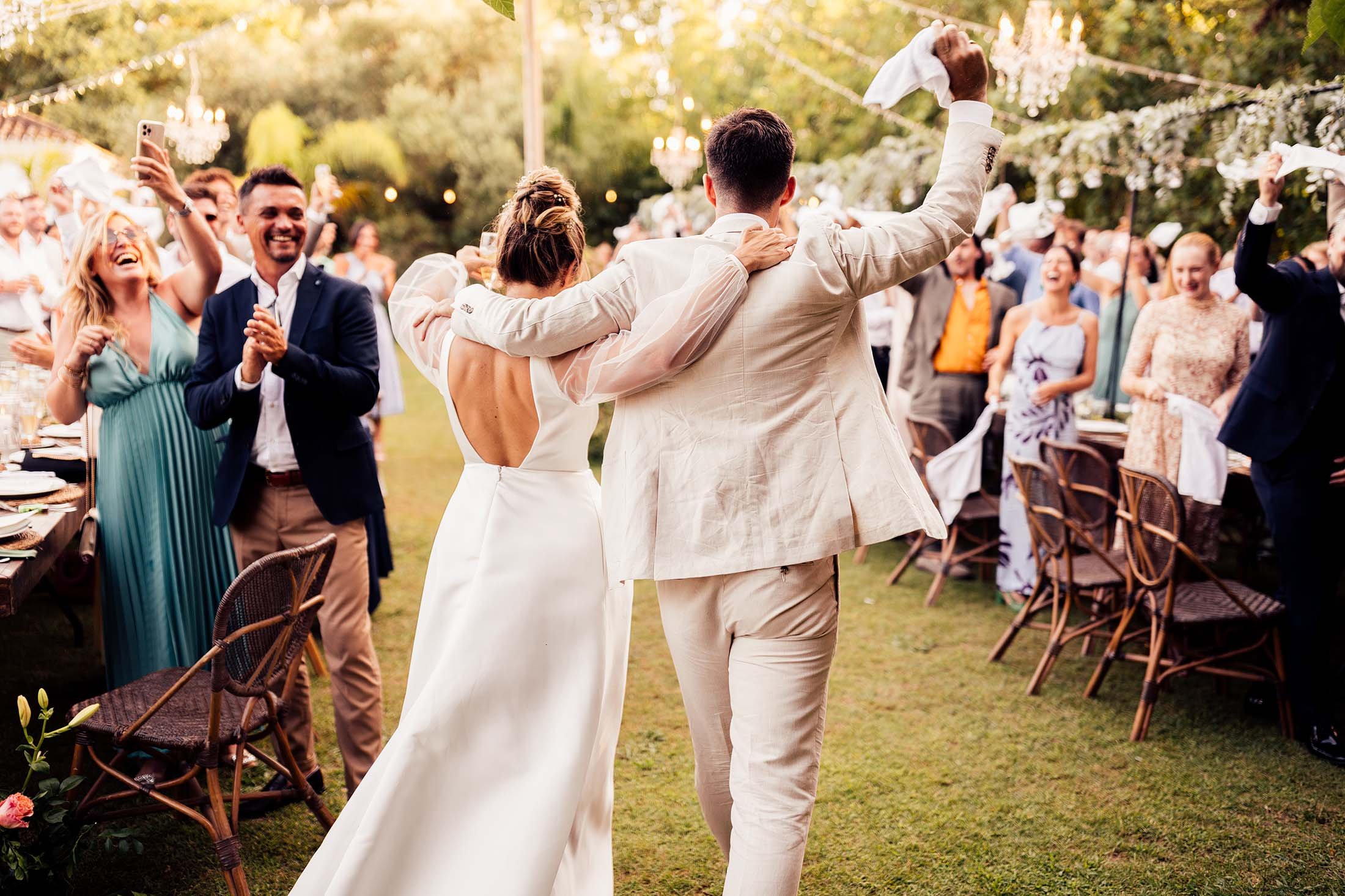 bride in jesus peiro dress and groom in cream linen suit enter outdoor dinner reception at finca monasterio wedding venue 