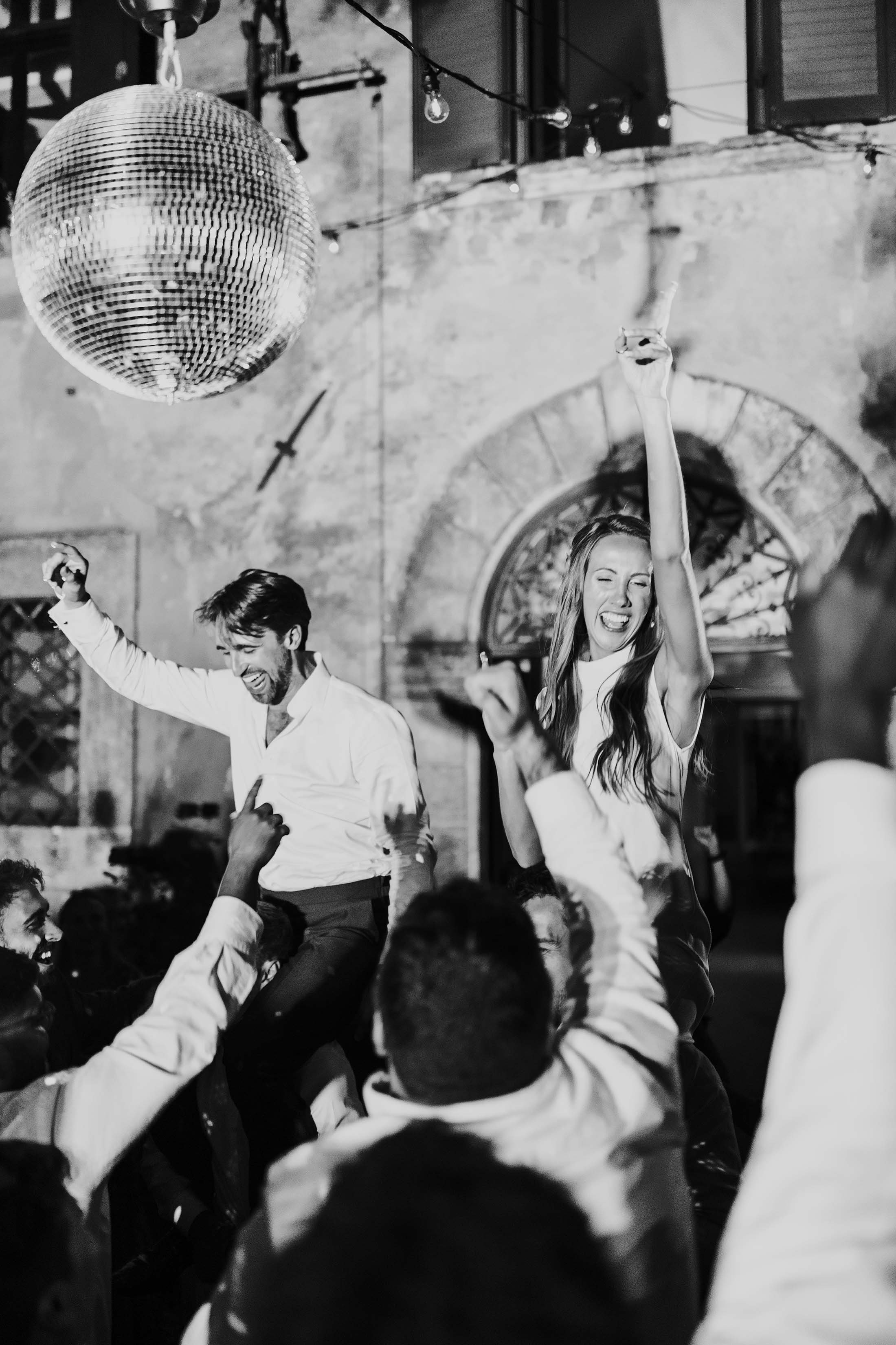 guests lift couple on dancefloor with disco ball installation