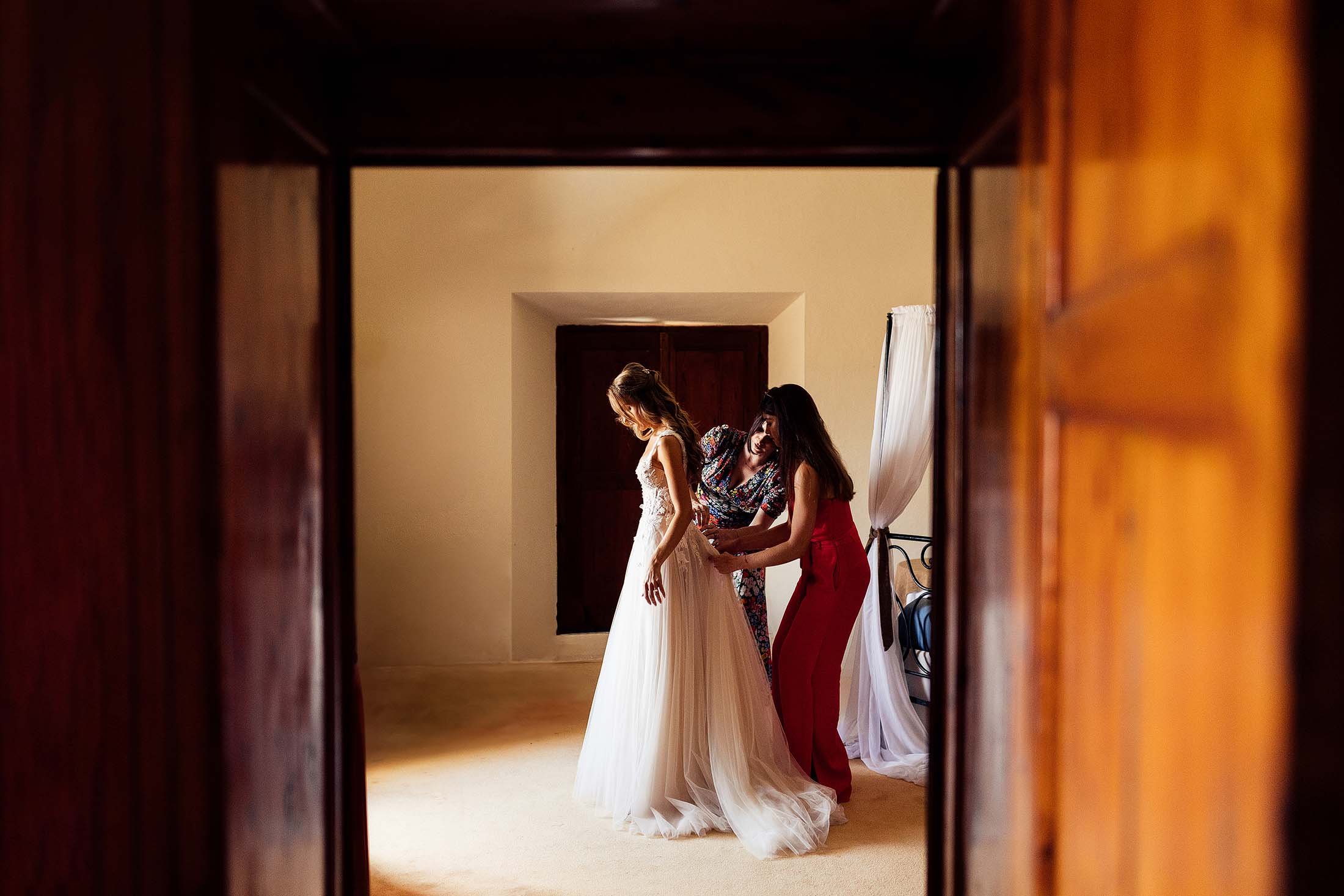 bridesmaids help bride into muse by berta dress