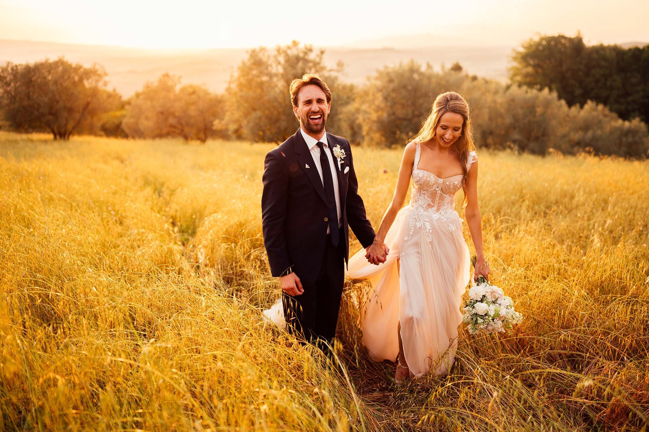 couple laugh during sunset photos in olive grove outside villa di ulignano