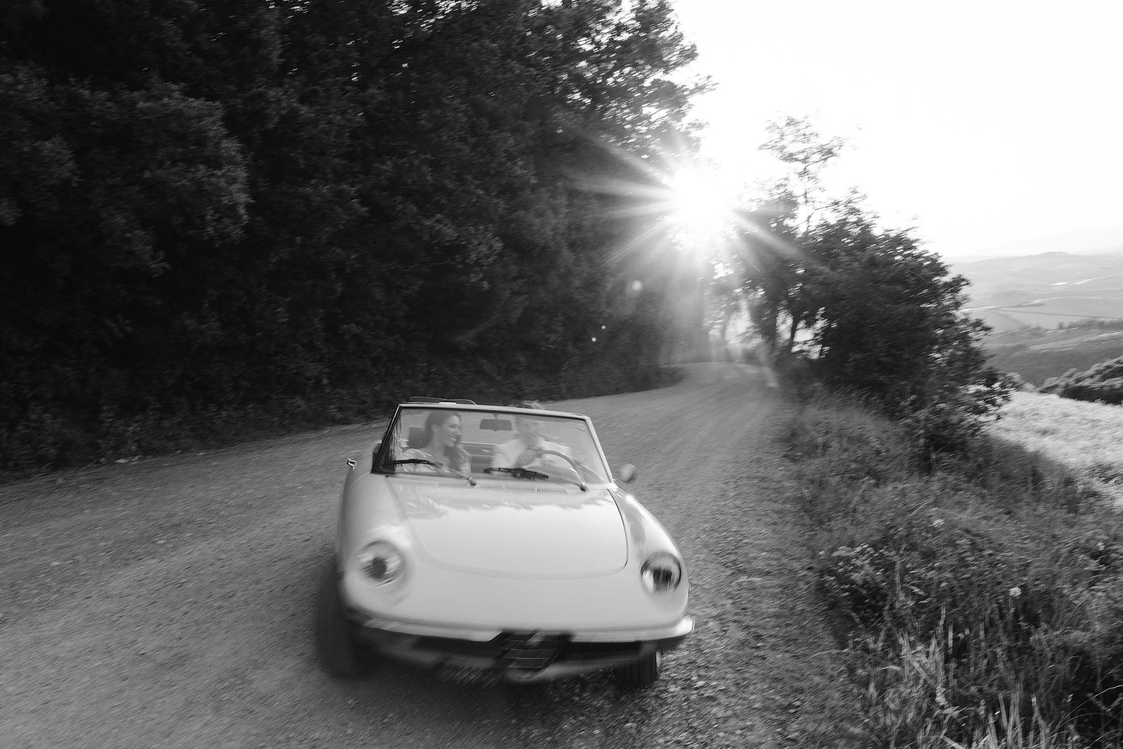 bride and groom drive in vintage alfa Romeo in Tuscany 