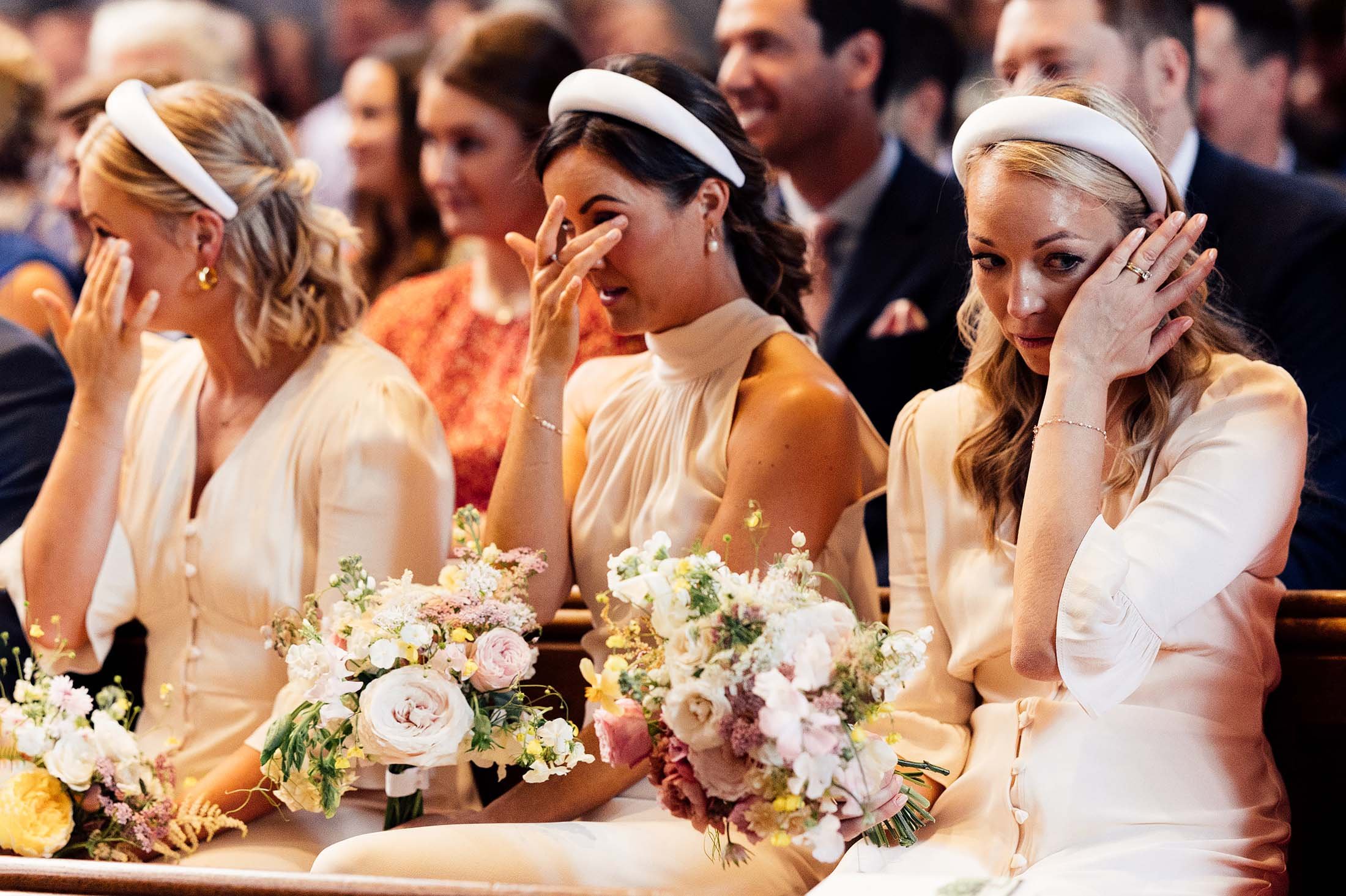 bridesmaids in white headbands cry during church service 