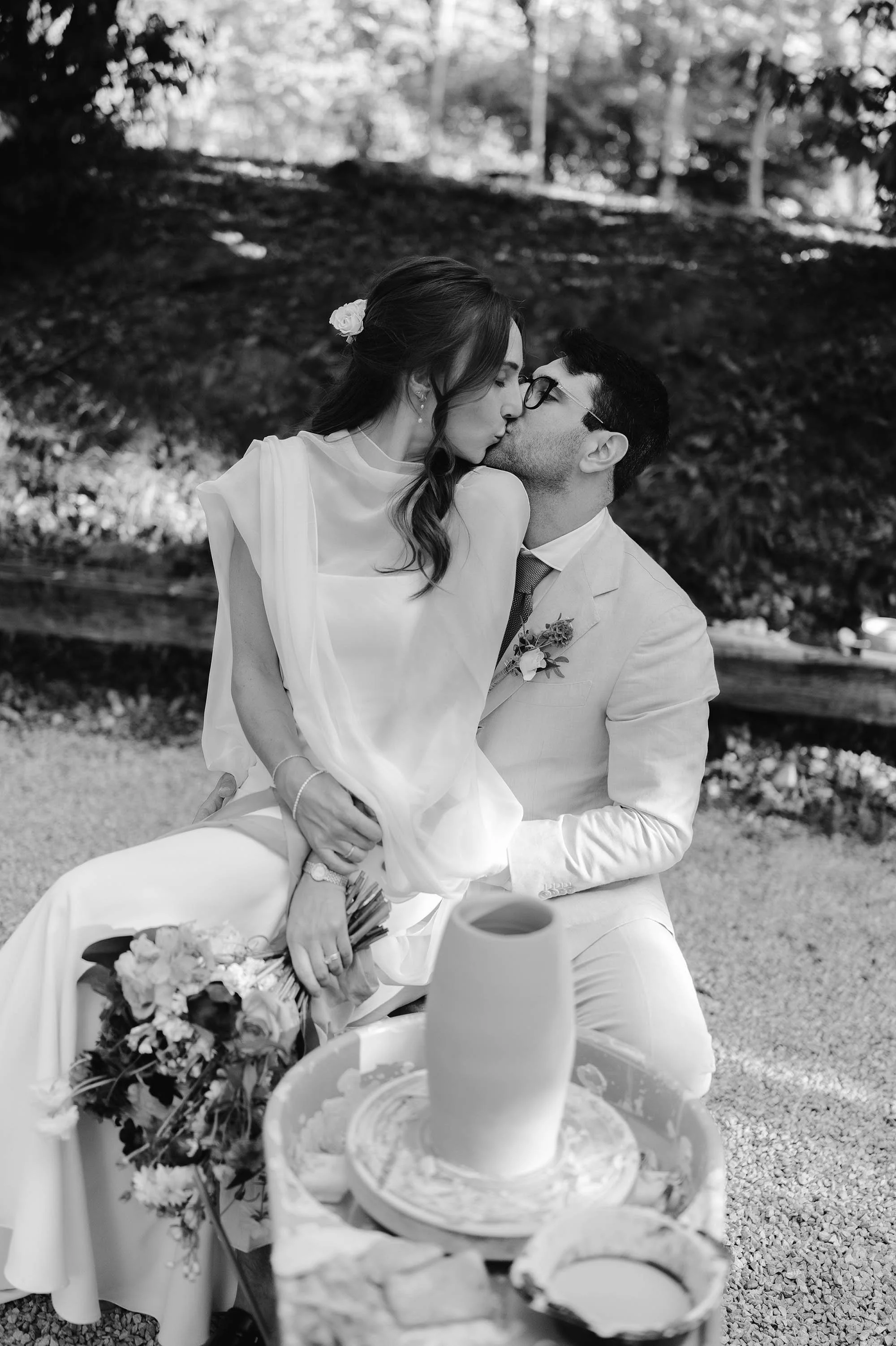 bride and groom kiss in front of pottery wheel owned by the groom