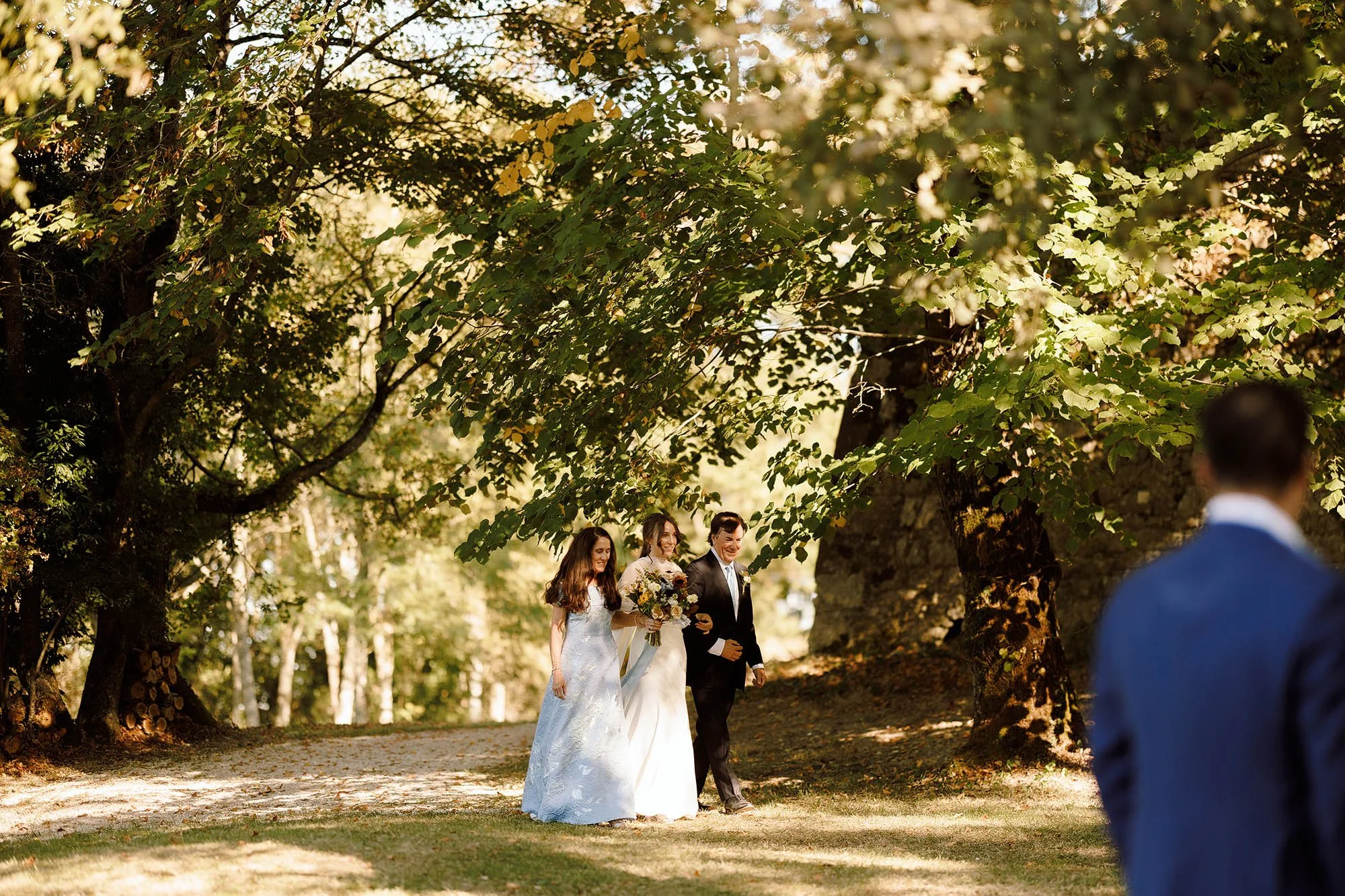 bride with parents walks down aisle for france wedding at chateau de lartigolle