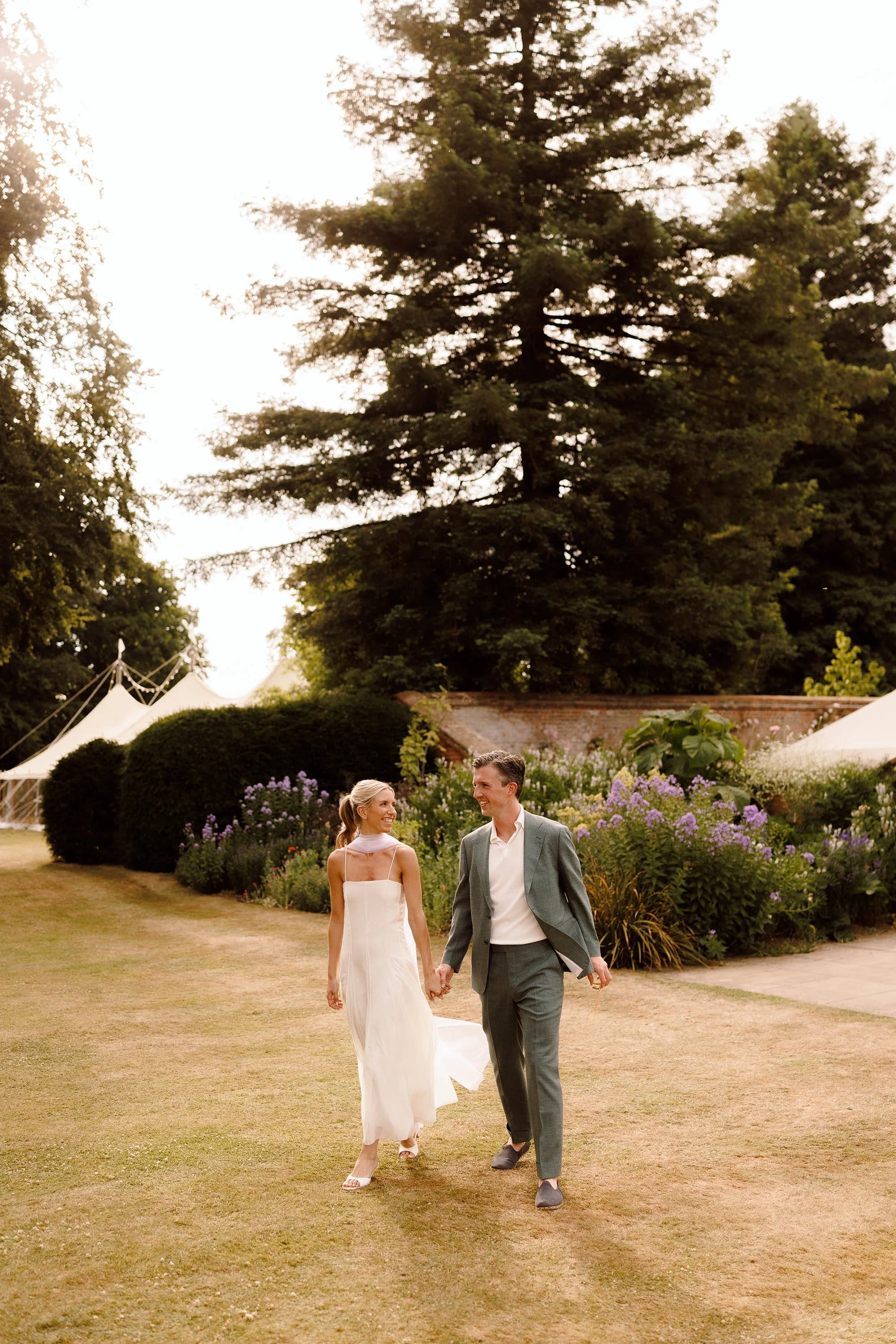 bride and groom walk in nevill holt estate gardens