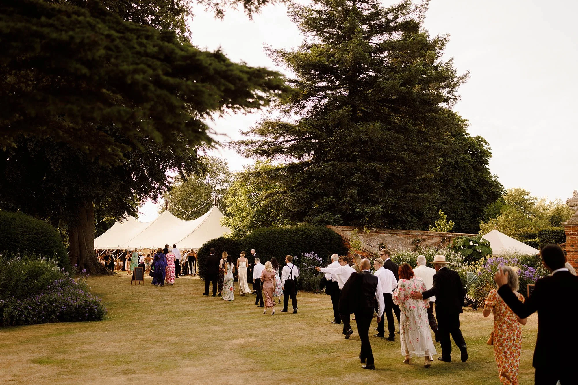 guests walk to marquee in gardens of nevill holt estate