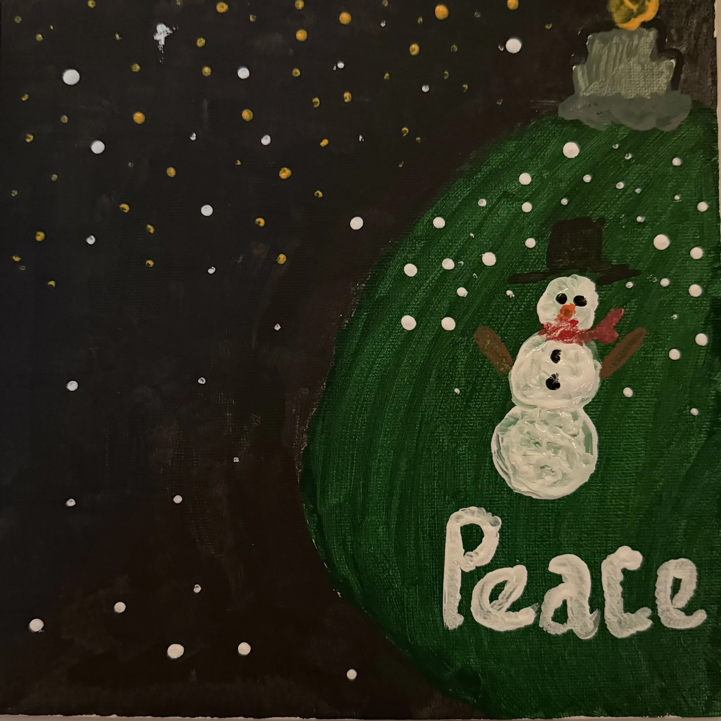 A painted Christmas ornament with a snowman and the word 'Peace' on it, with falling snow in the background.