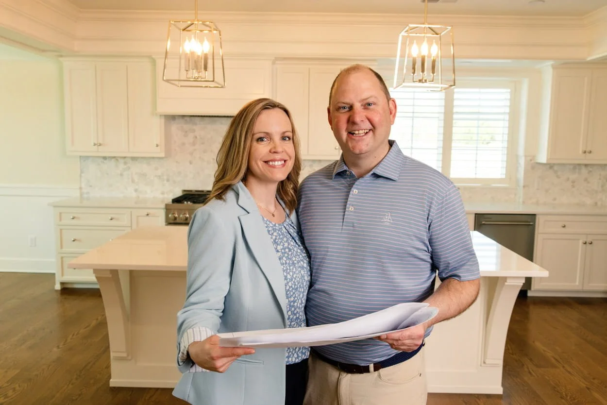 Two people holding home plans inside a newly built kitchen in Lawrence, Kansas, during the Mid-America Bank Community Leader Award project.