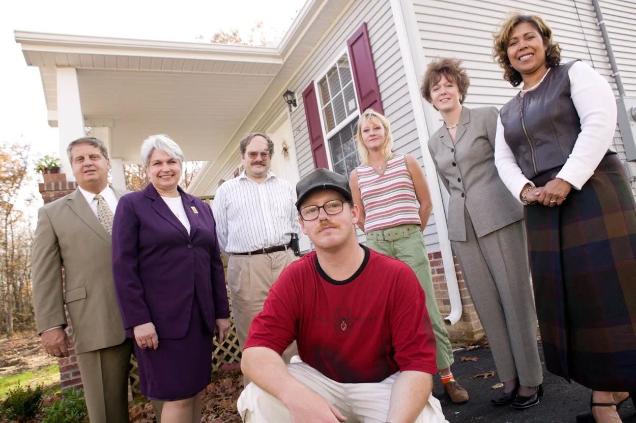 Homeowner standing with local bankers and community representatives in front of a house in Crossville, Tennessee during 2004 annual report photography project