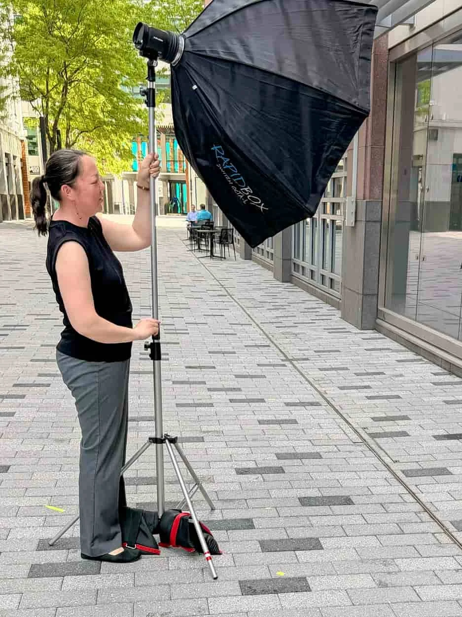 Photography assistant adjusting lighting equipment during an outdoor portrait production.